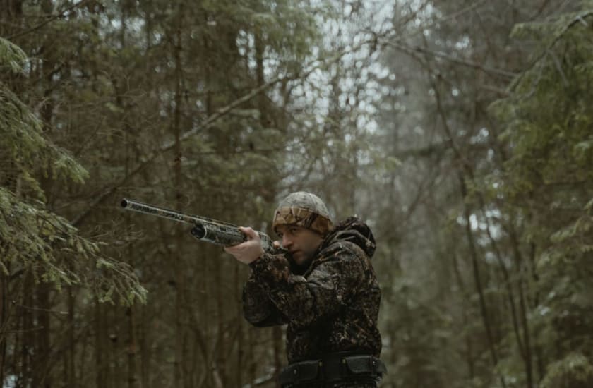 man in camo aiming a rifle in a snowy forest | Tima Miroshnichenko, via Pexels