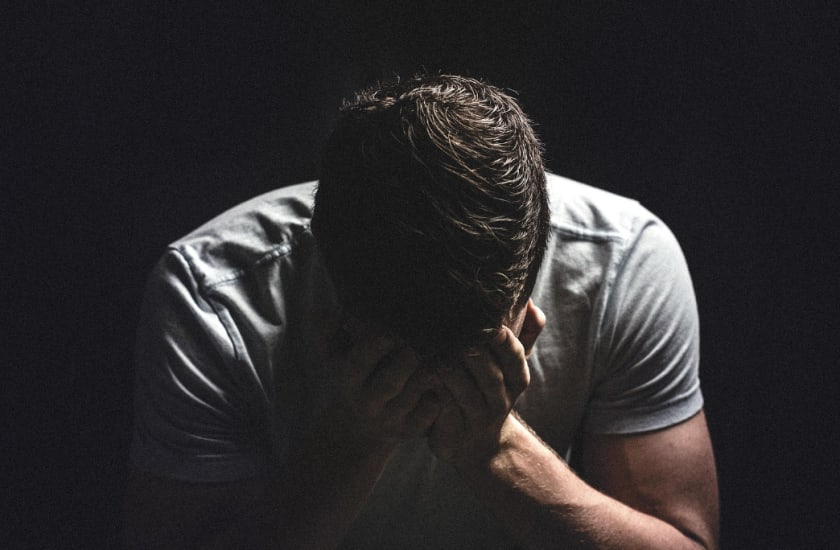 man with head in hands in a dark room