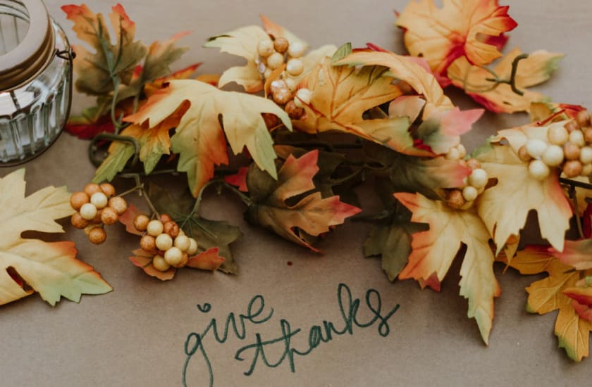the words 'give thanks' written out on a table with fall leaves surrounding it