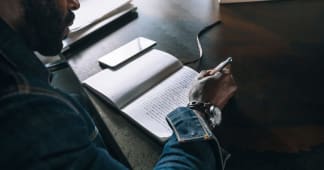 over-shoulder of a man writing in a journal