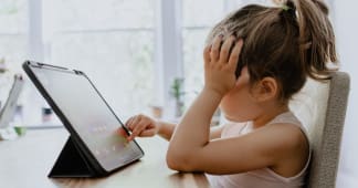 child touching an ipad while holding her face in her hand