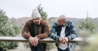 Father and son talking while leaning on a fence post