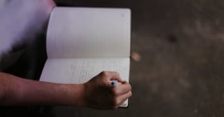 hands holding a journal and pen