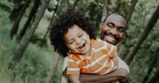 dad holding child and both laughing facing the camera