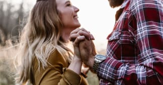 man and wife facing each other smiling and holding hands