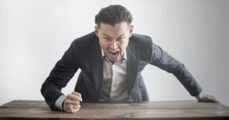 Man pounding his fist on a table in anger