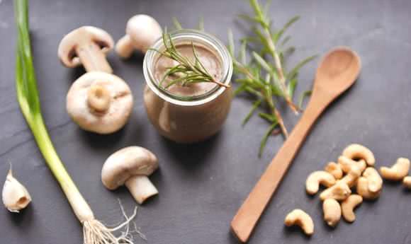Champignoncremesuppe im Glas auf dunkler Schieferplatte mit Zutaten.