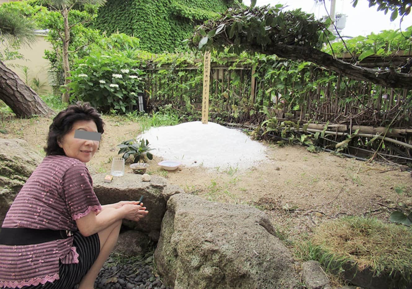 田辺市内にある自宅の庭に建つ愛犬の墓に、線香をあげる家政婦。6月7日、和歌山県警は墓を掘り起こした