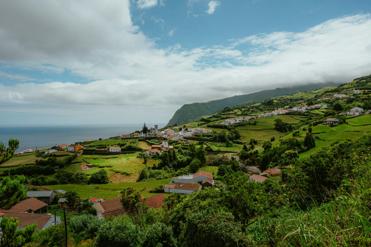 Small green walled fields on a coastal slope running down to a blue sea