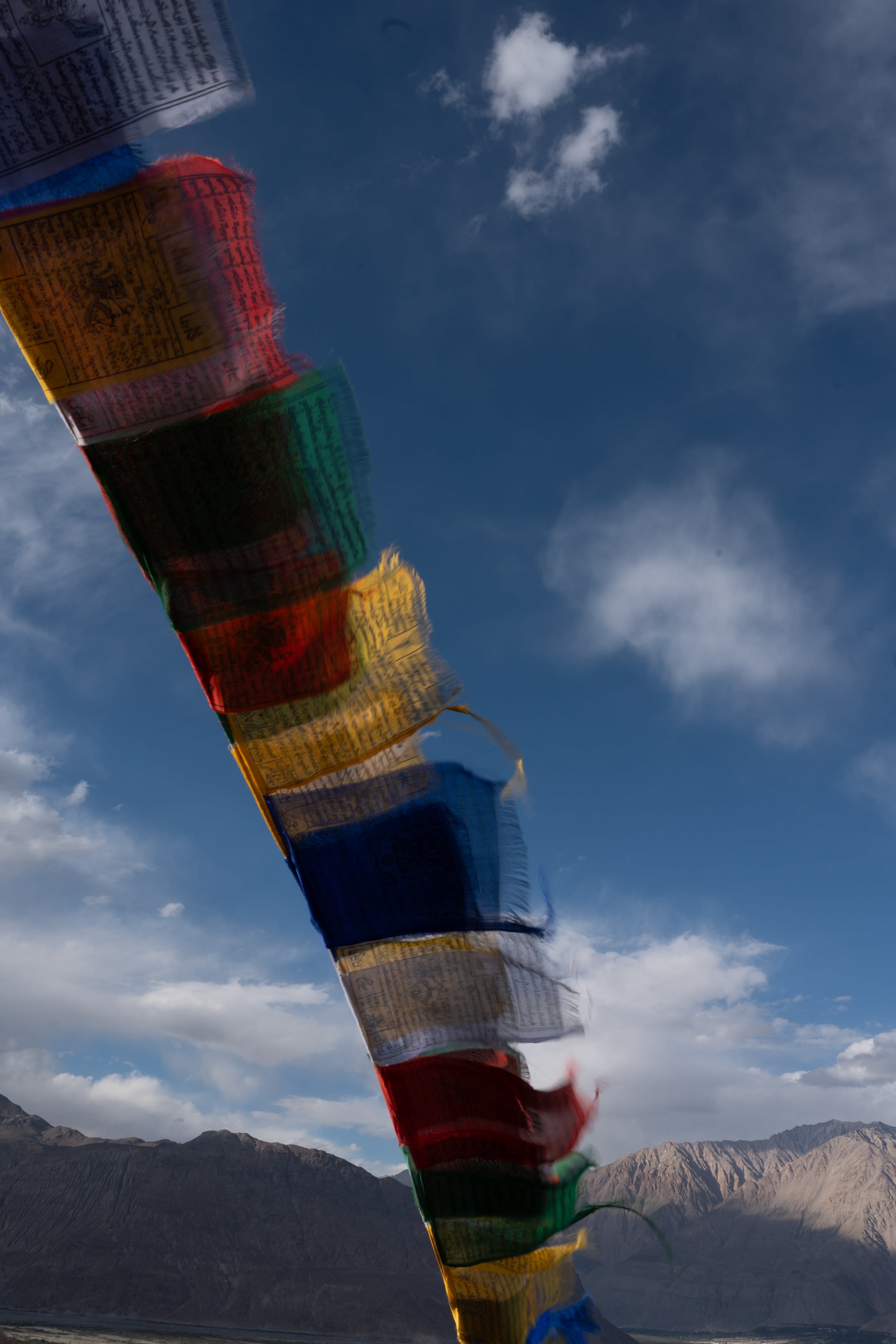 A column of prayer flags leaning across a blue sky