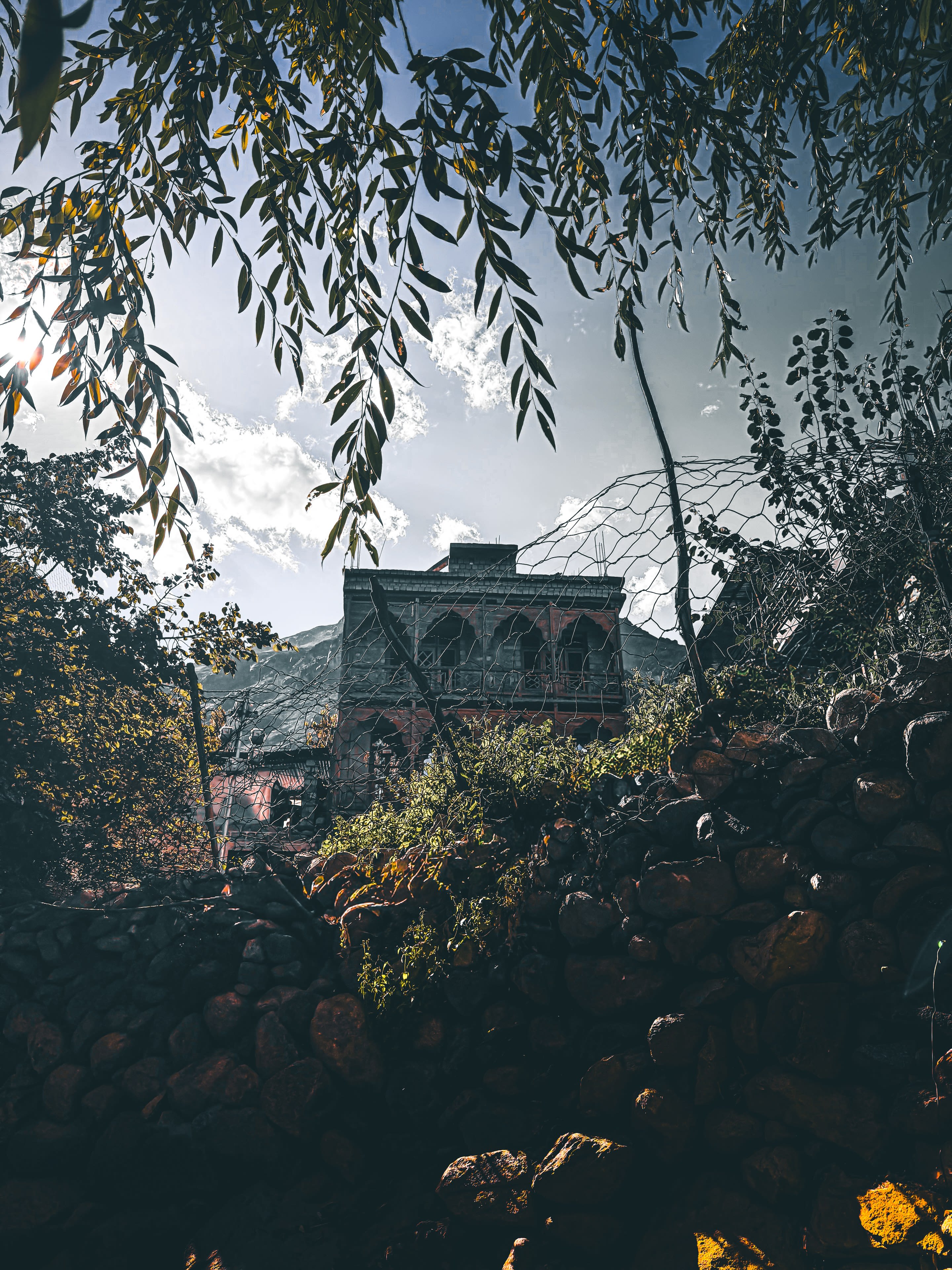A stone building seen through hanging willow branches