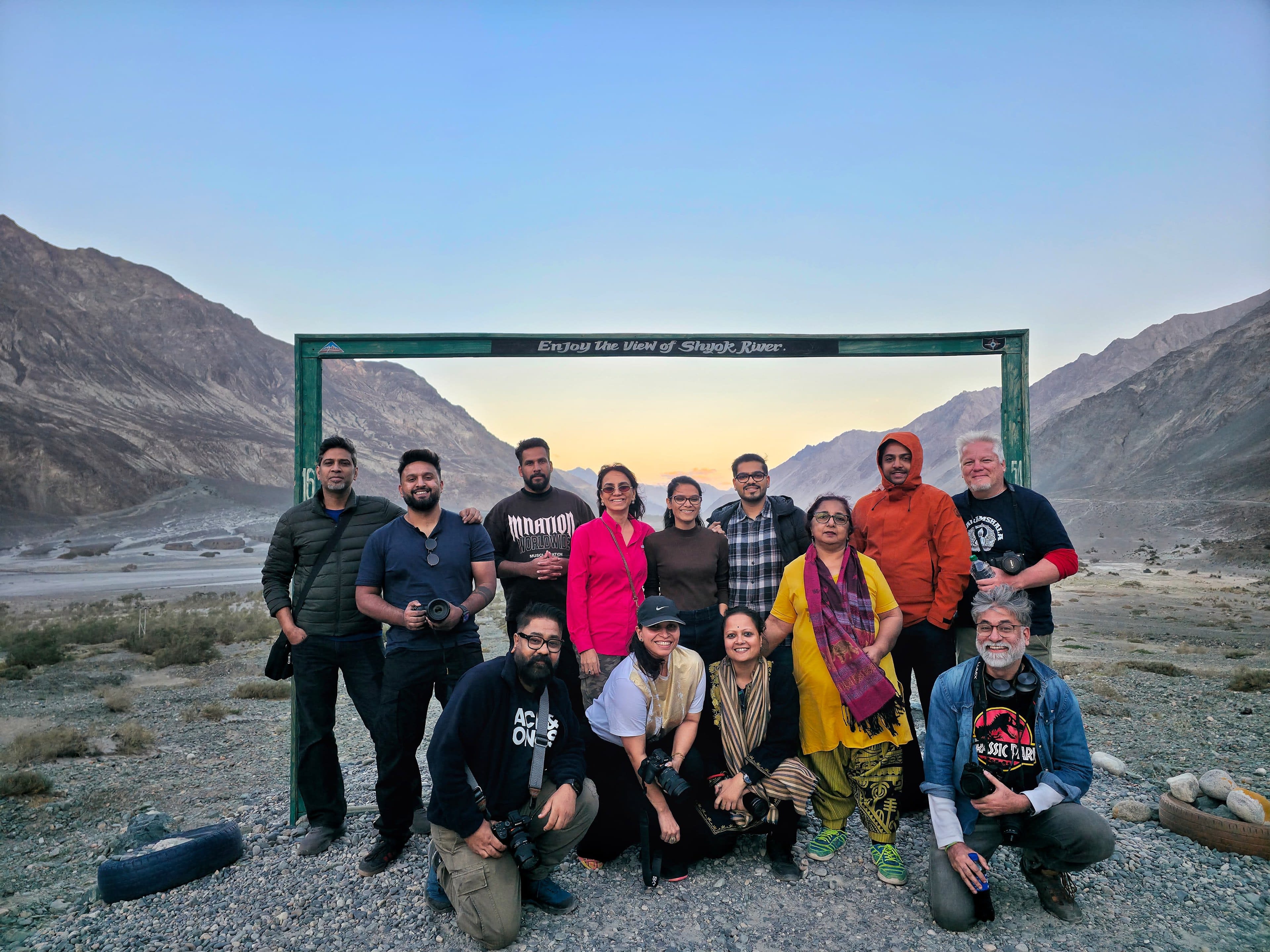 A travel group posing at a valley gate signboard at dusk