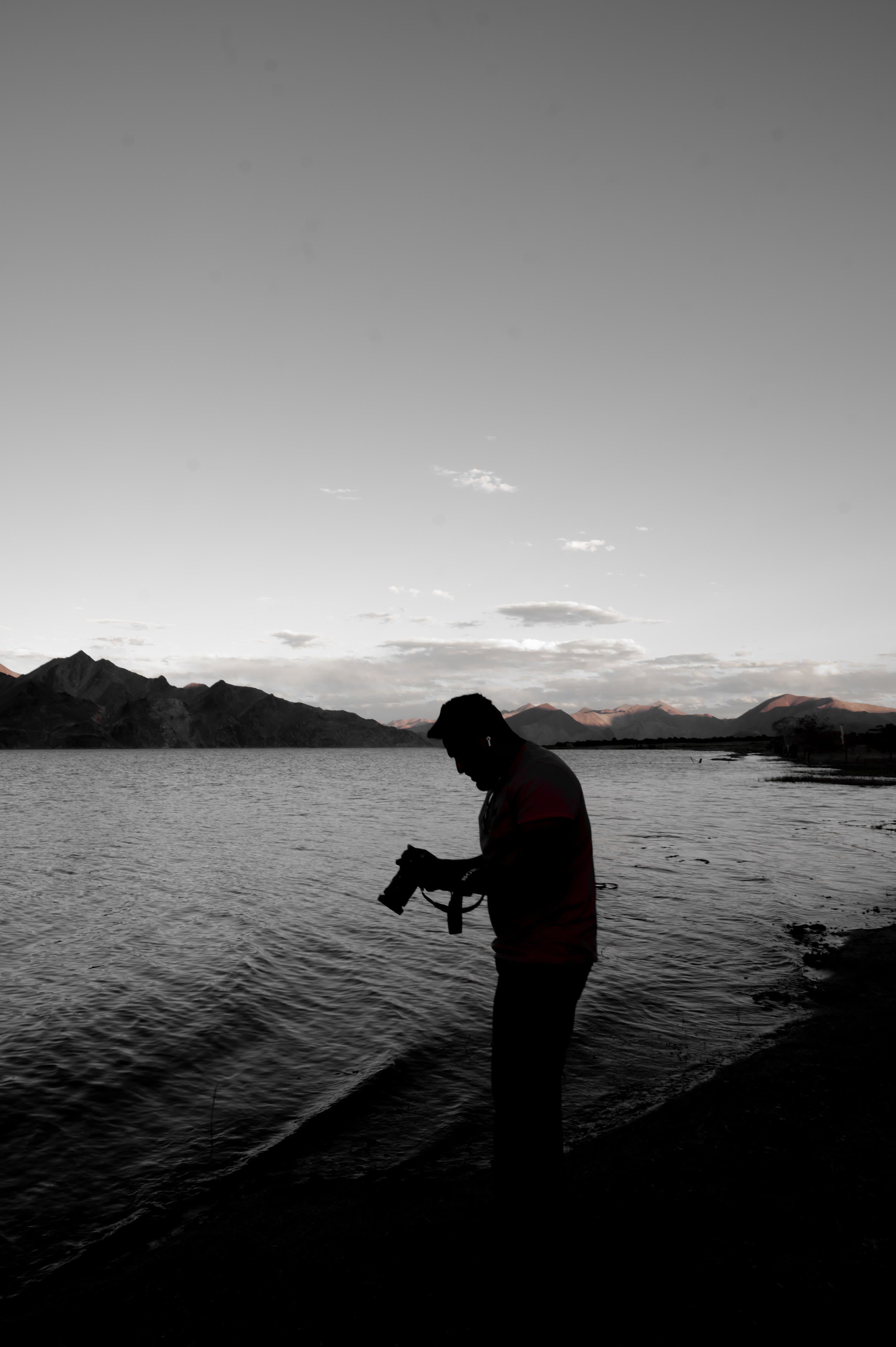A person with a camera standing at a windblown lake edge