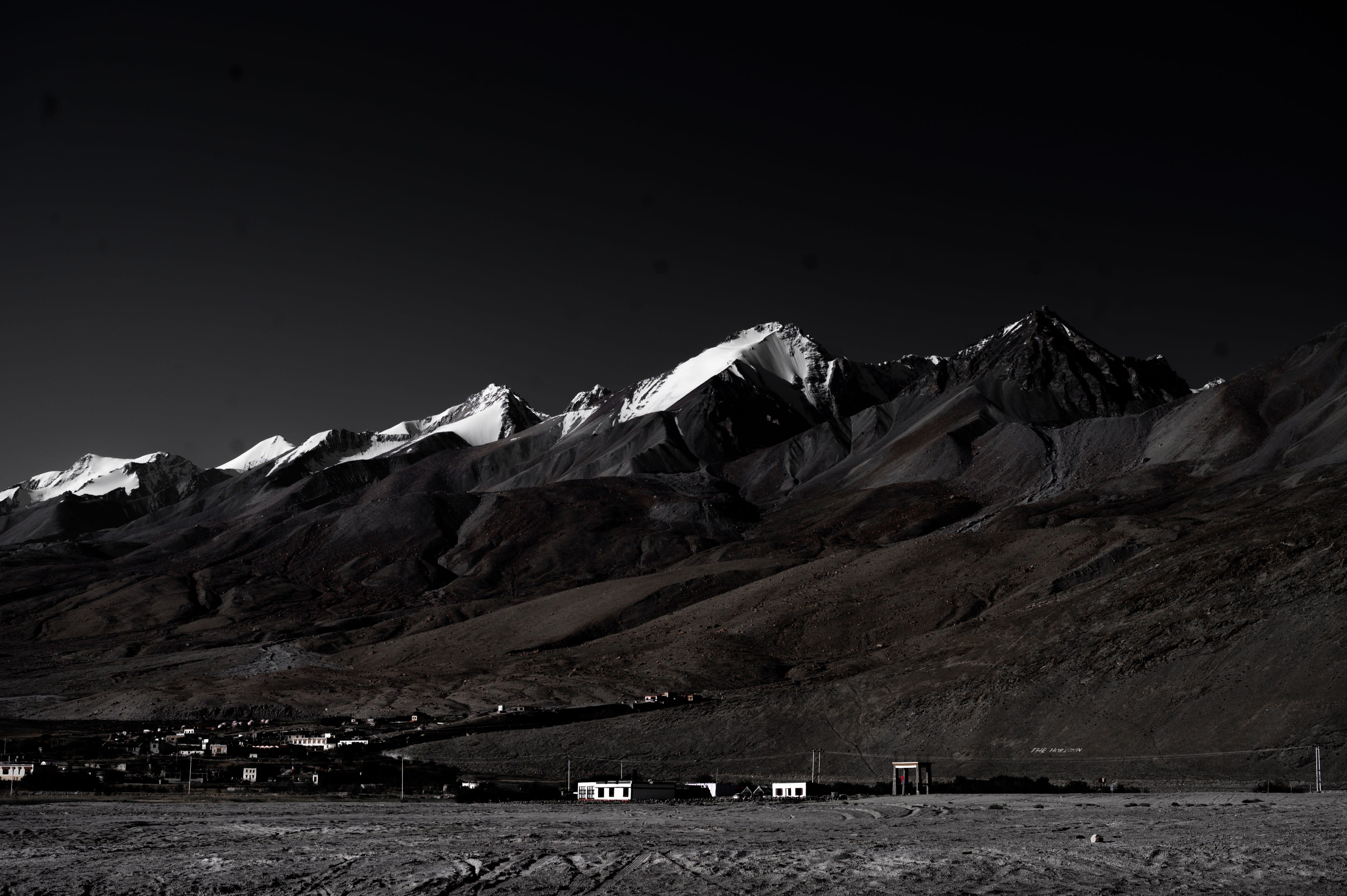 Snow peaks above a dark valley and lakeside camp
