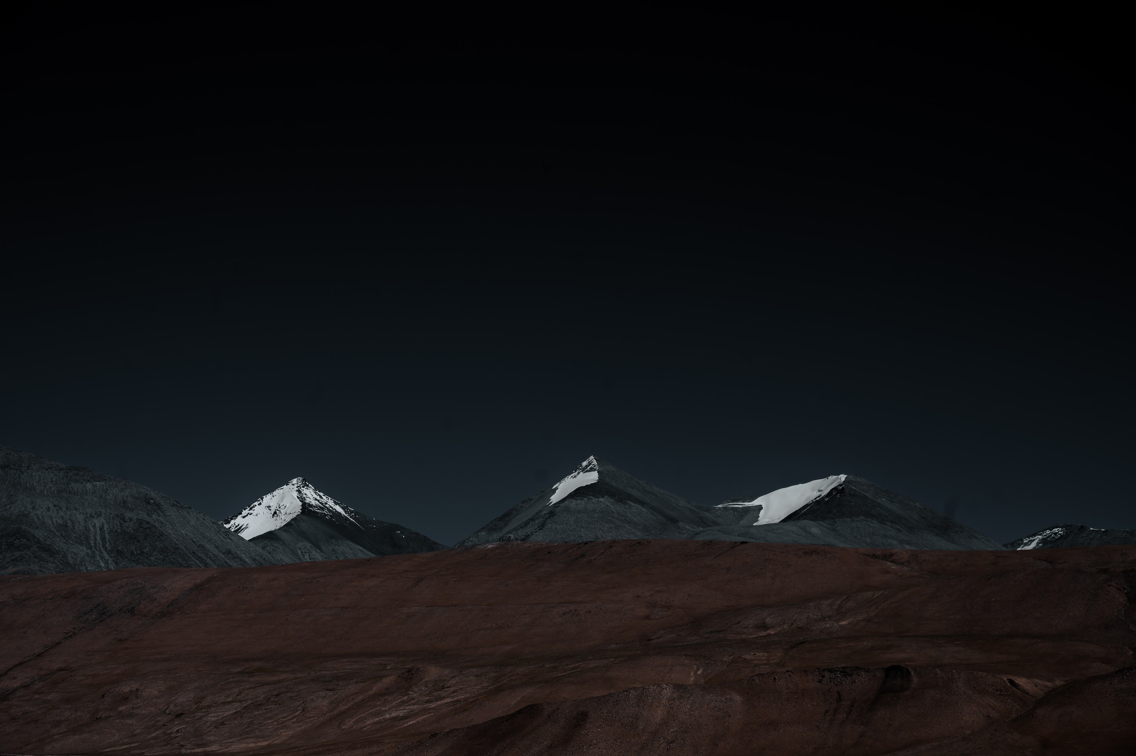 A row of snow mountains above a brown high-altitude plain