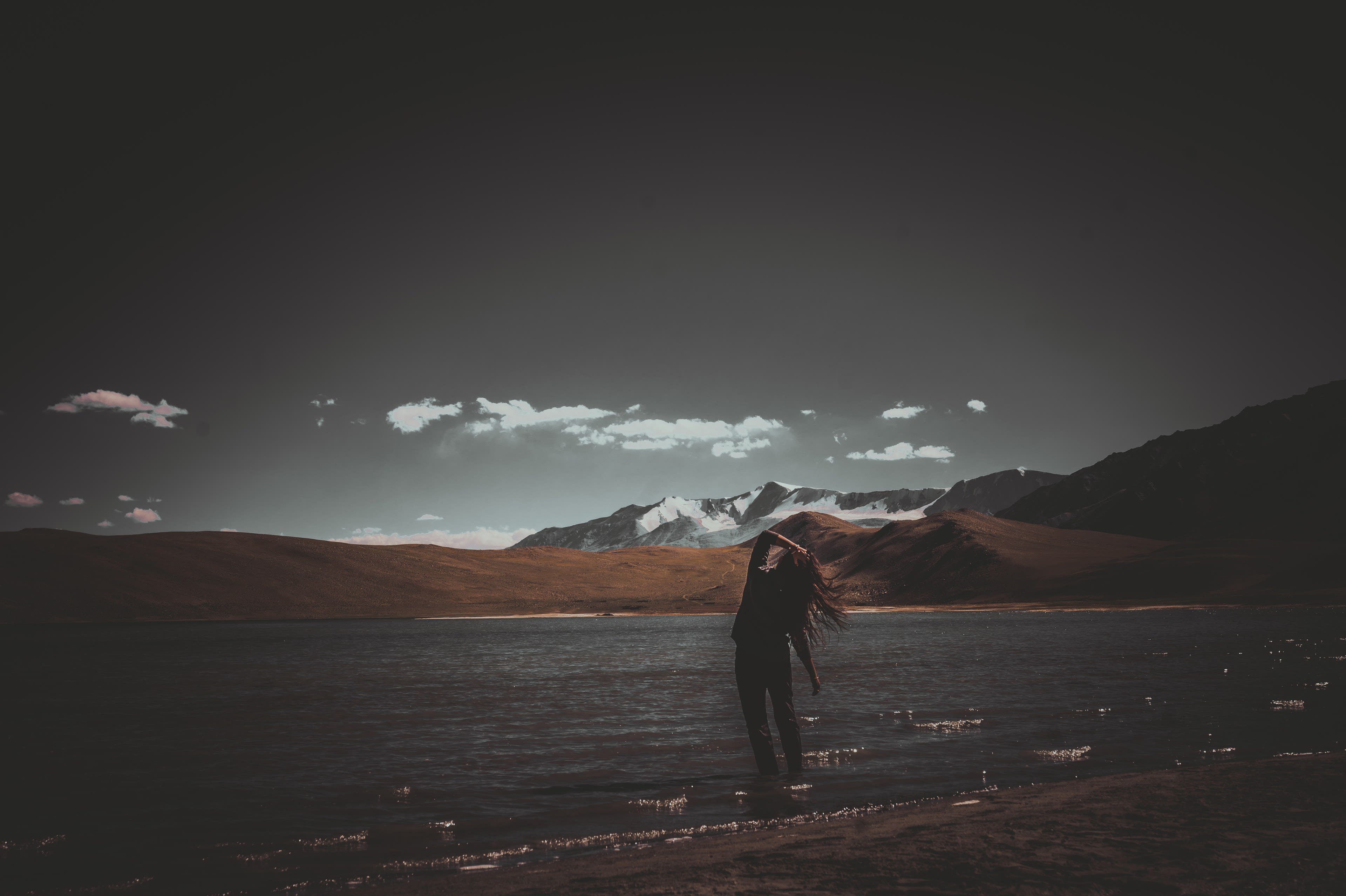A person photographing bare hills under moving cloud