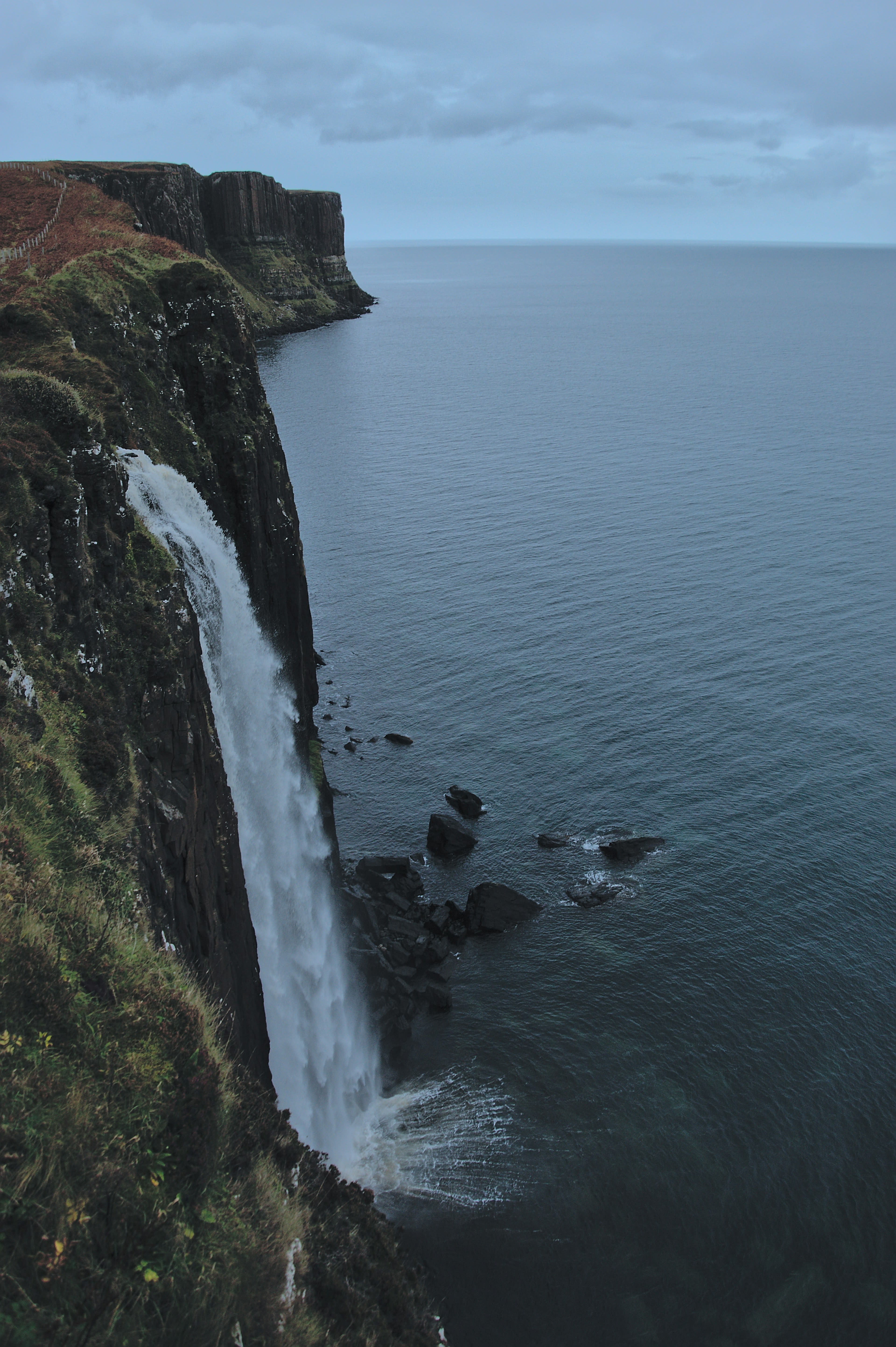 A waterfall dropping from a green clifftop straight into the sea