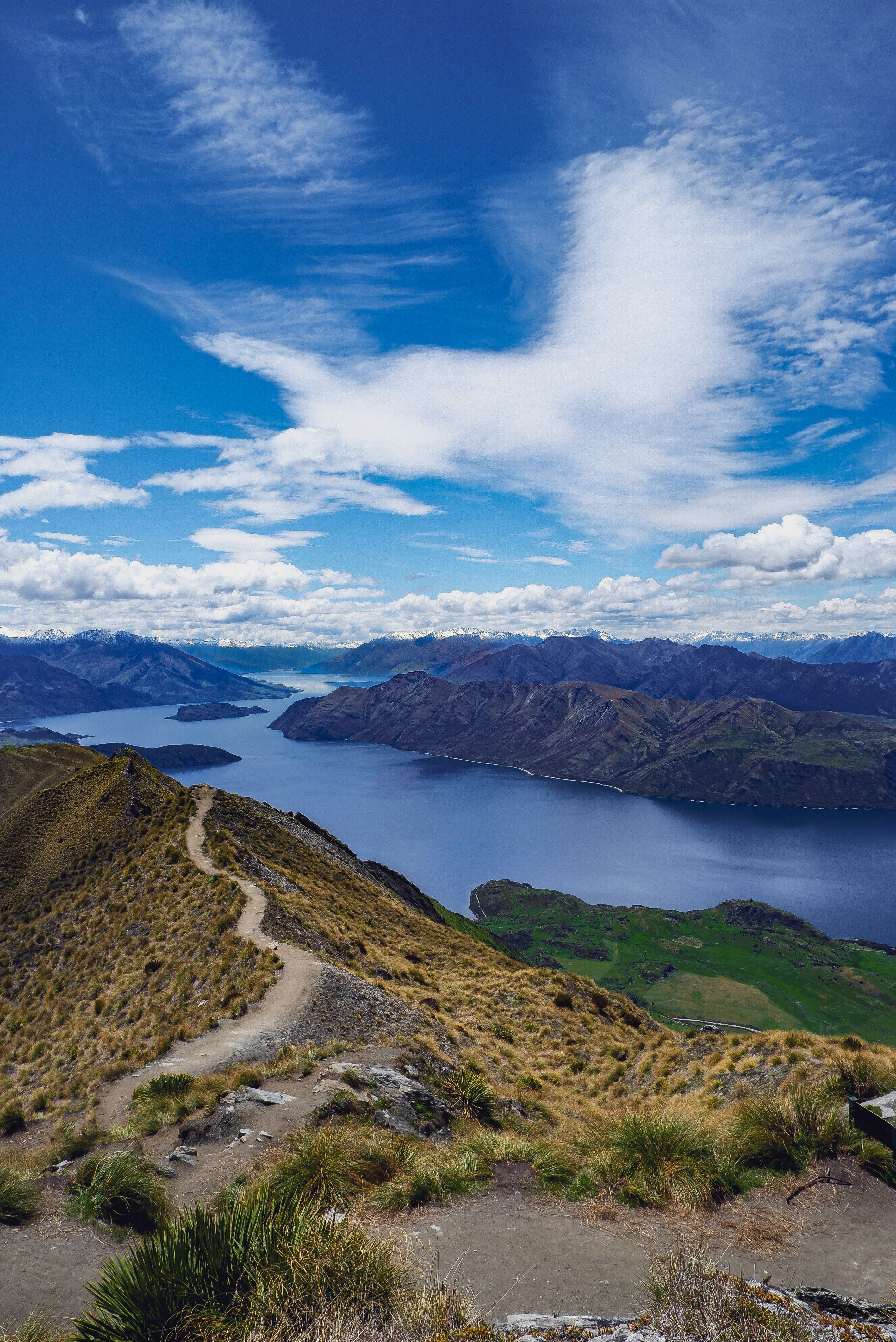 A trail winding along a high ridge above a blue lake and mountains