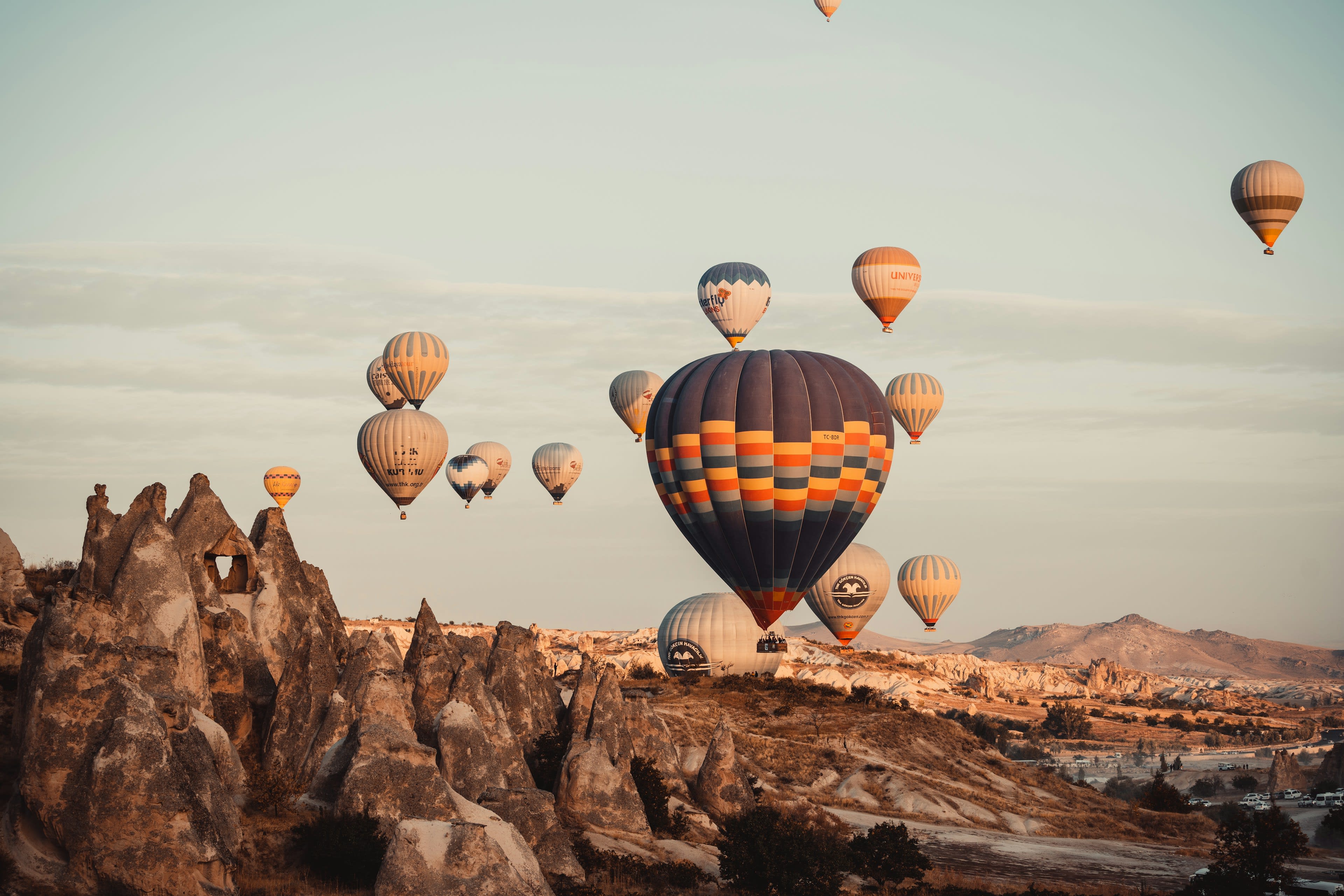 Hot air balloons drifting over golden fairy chimney rock formations