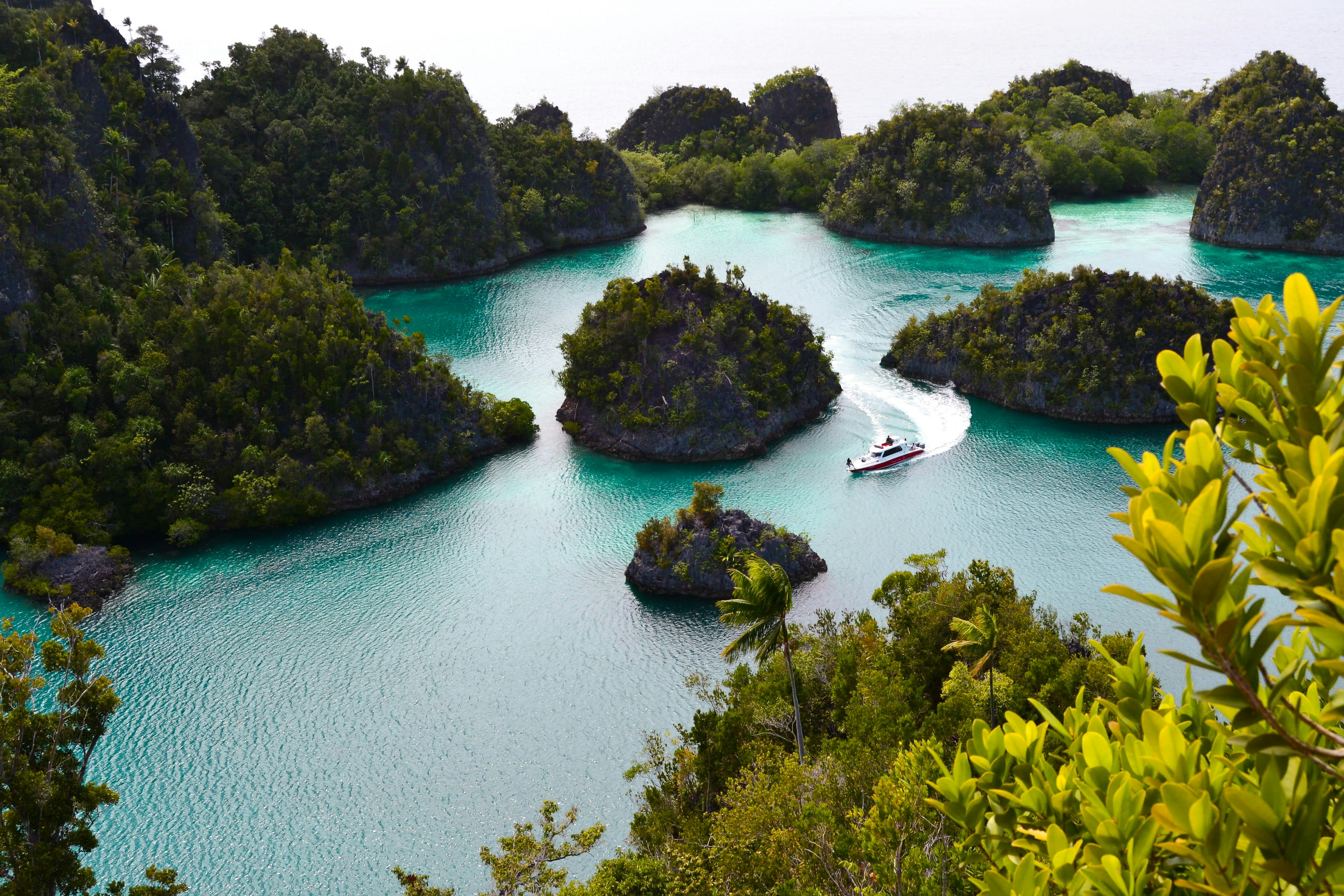 A boat in a turquoise lagoon among steep jungle-covered karst islets