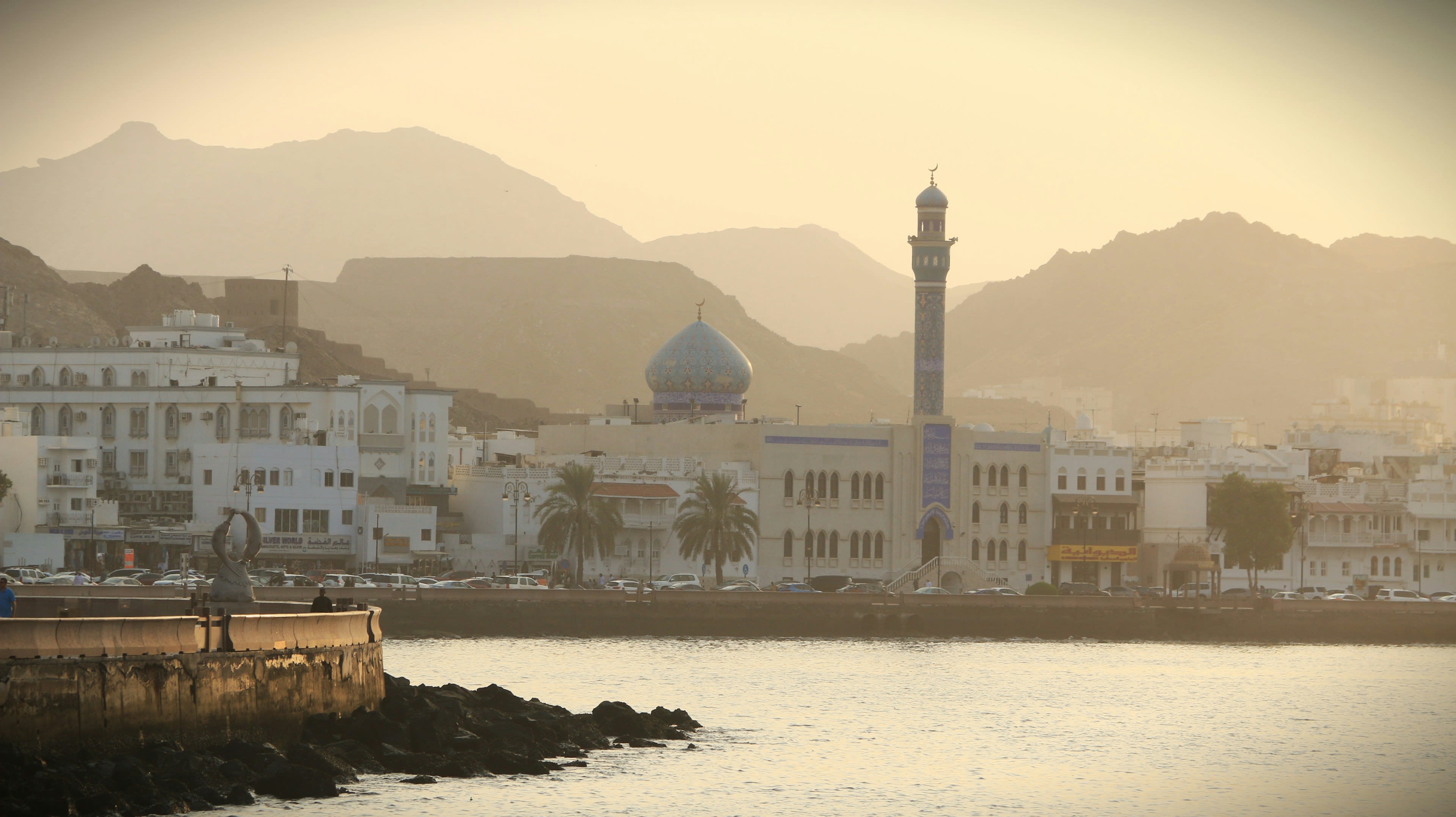 A hazy harbour morning with a minaret and hills in soft grey light