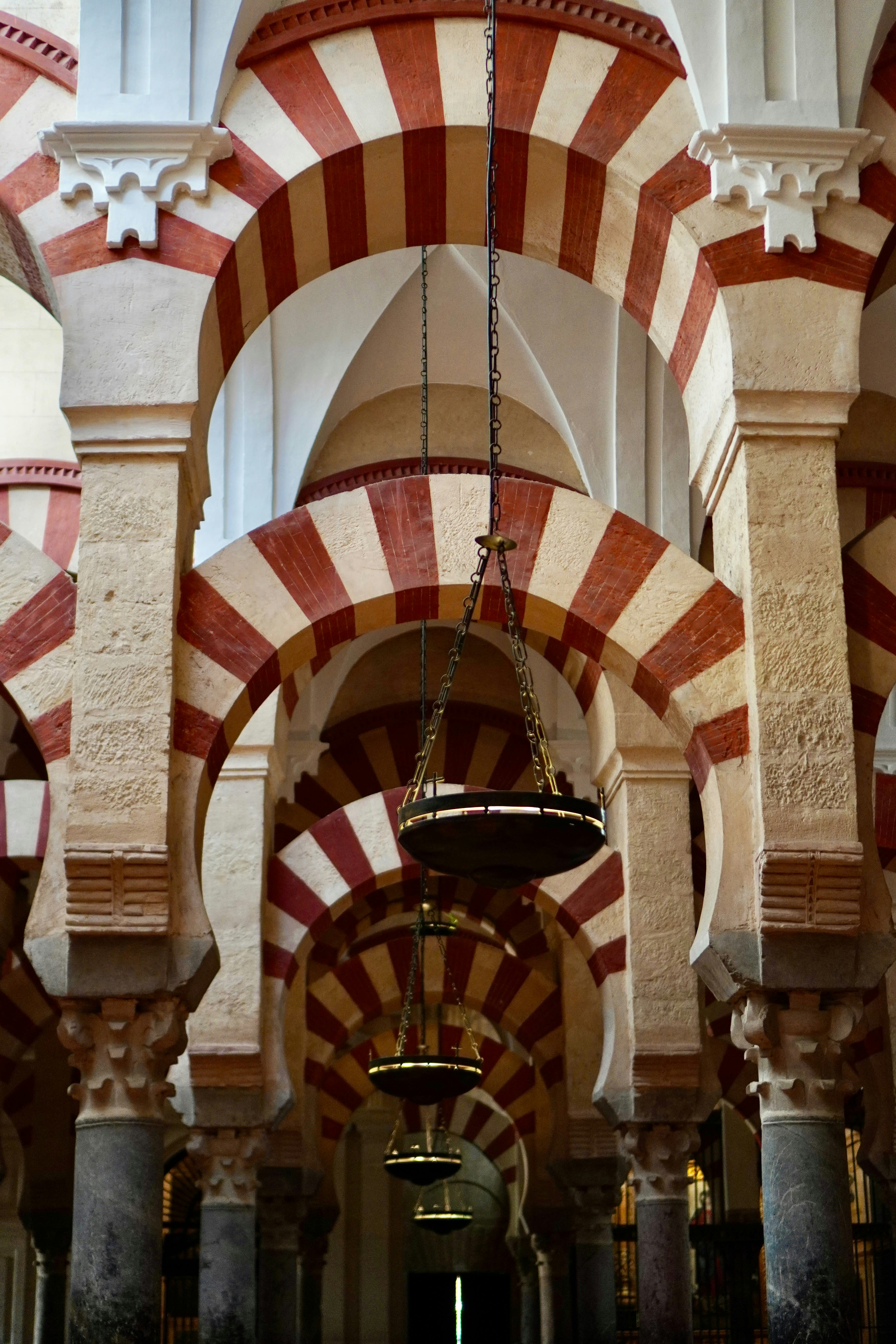 Red and white striped arches repeating through a dim prayer hall