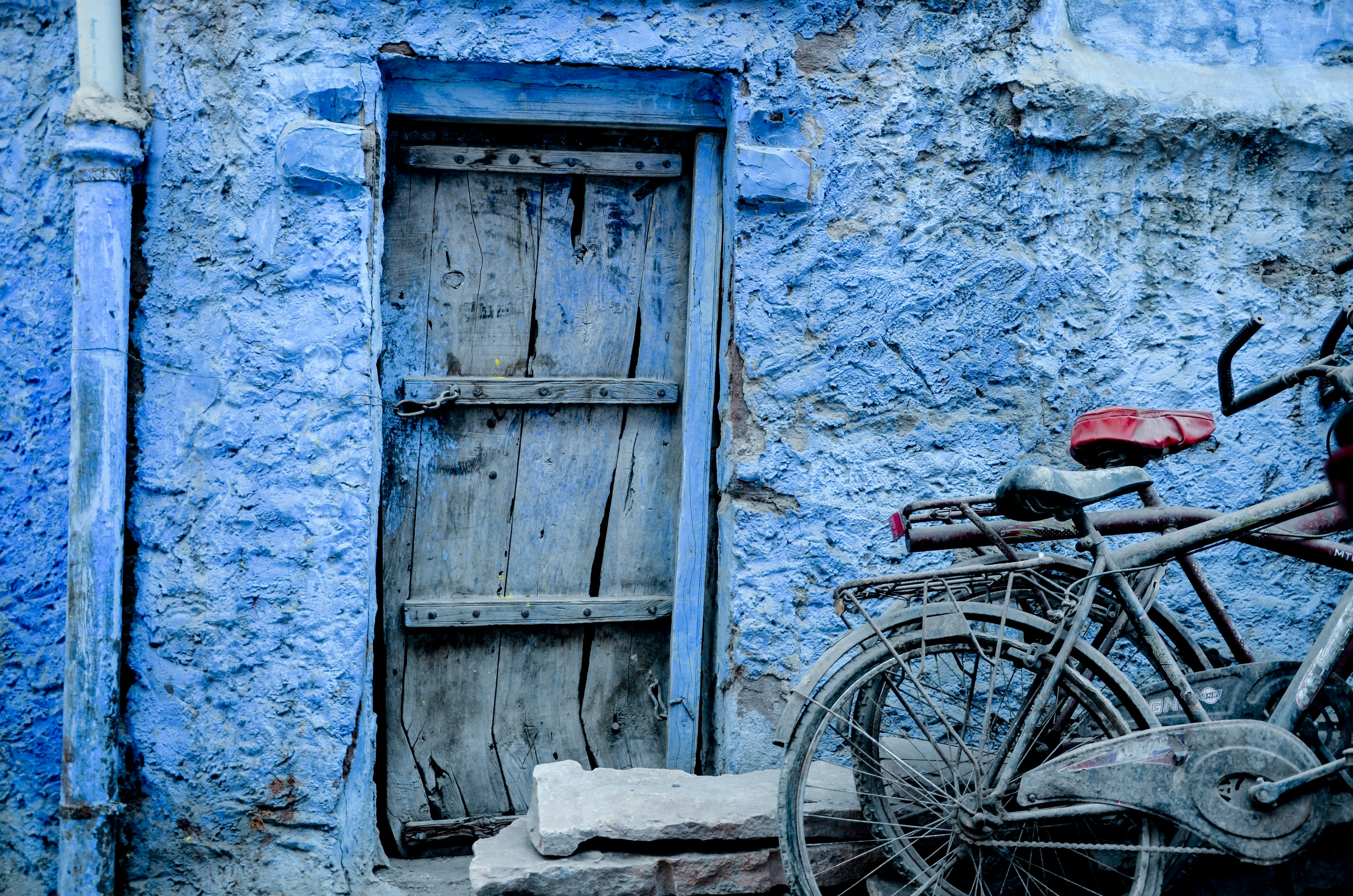 Bicycles leaning against a weathered blue wall and door