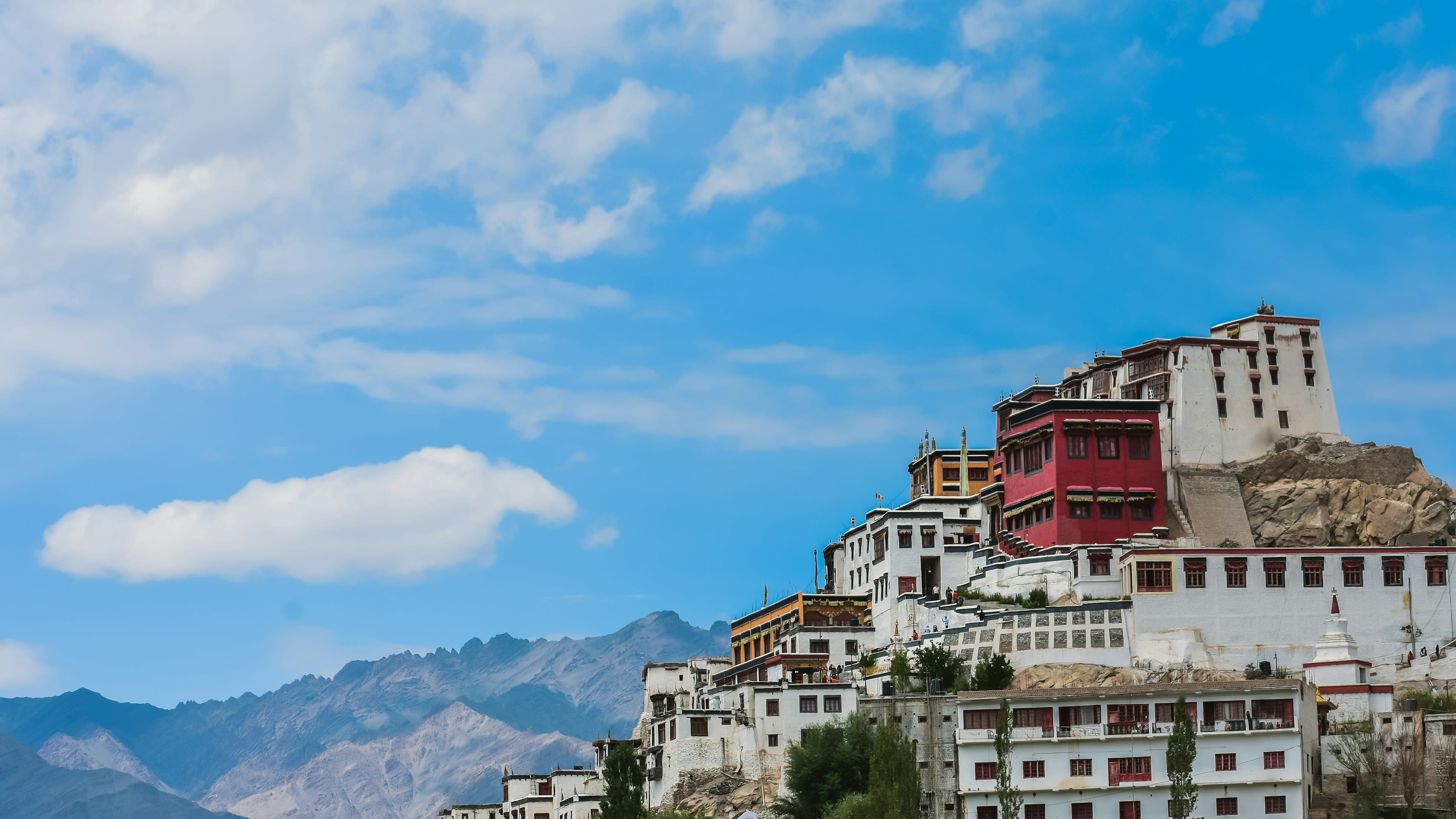 A whitewashed Buddhist monastery rising in tiers up a hillside above a valley