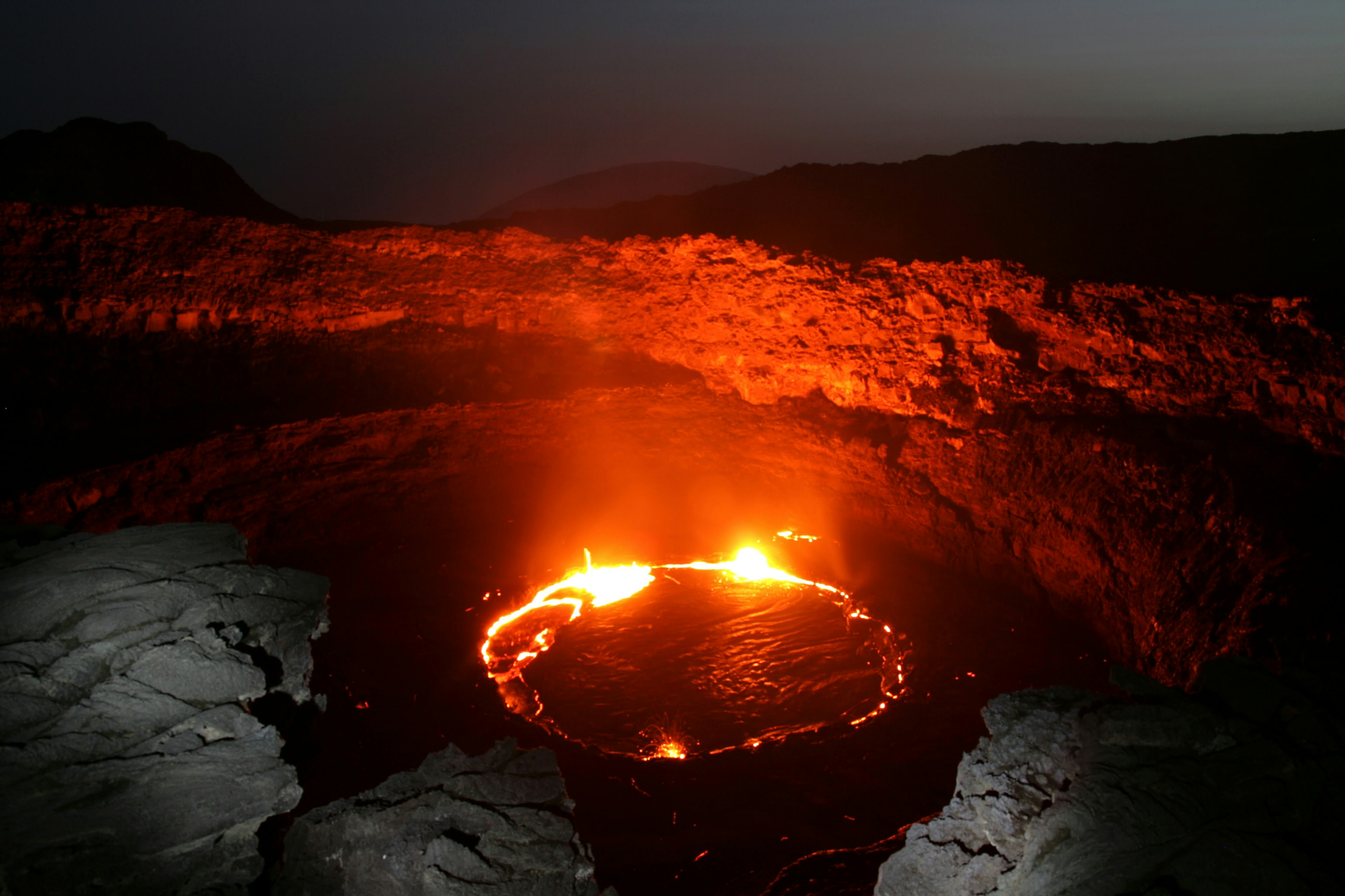 The glowing red lava lake of Erta Ale seen from the crater rim at night