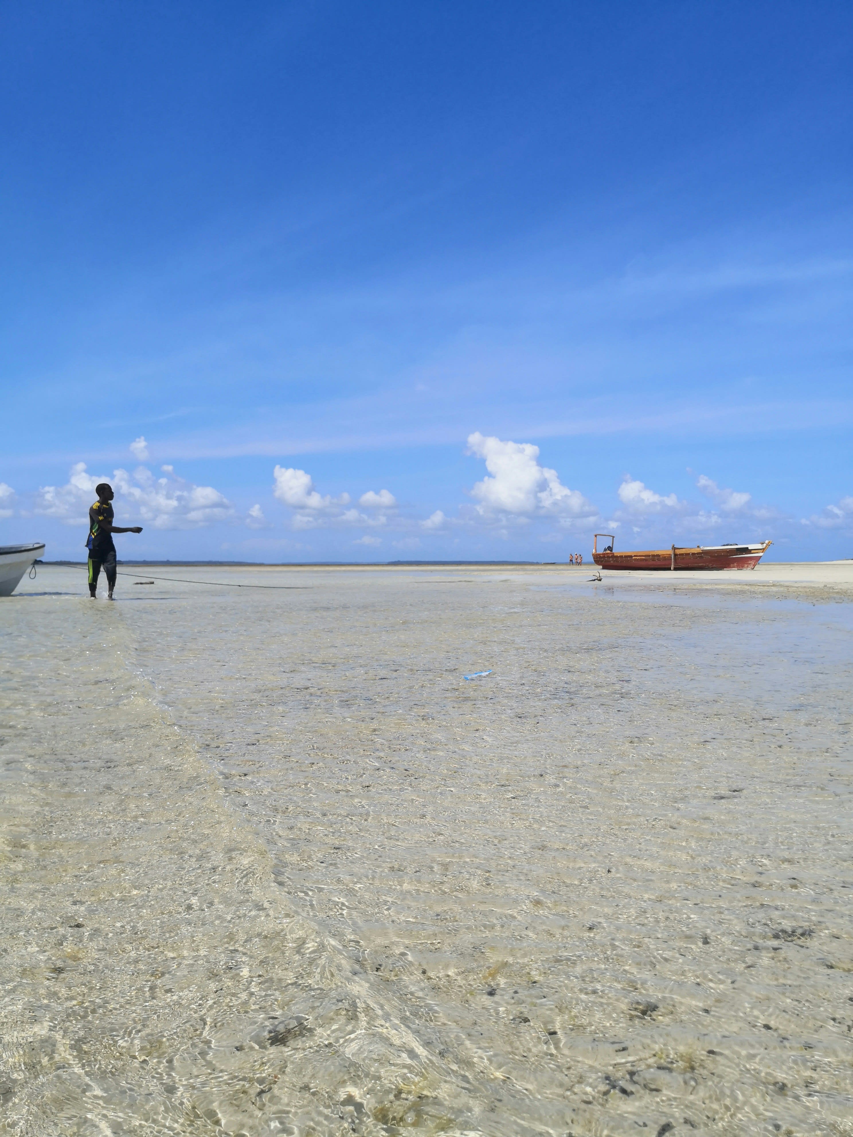 A person standing far out on white tidal flats under a big sky