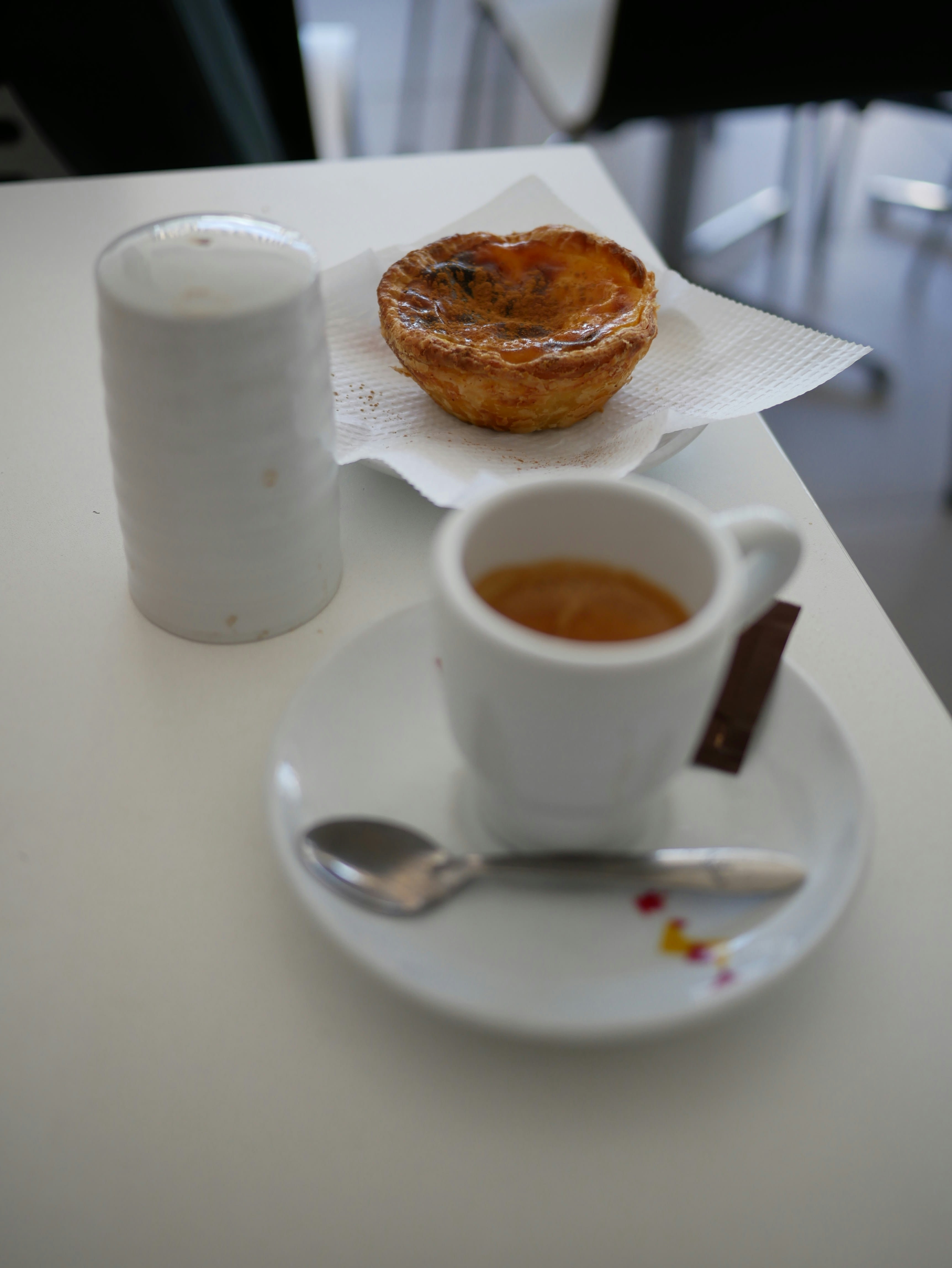 An espresso and a custard tart on a small café table