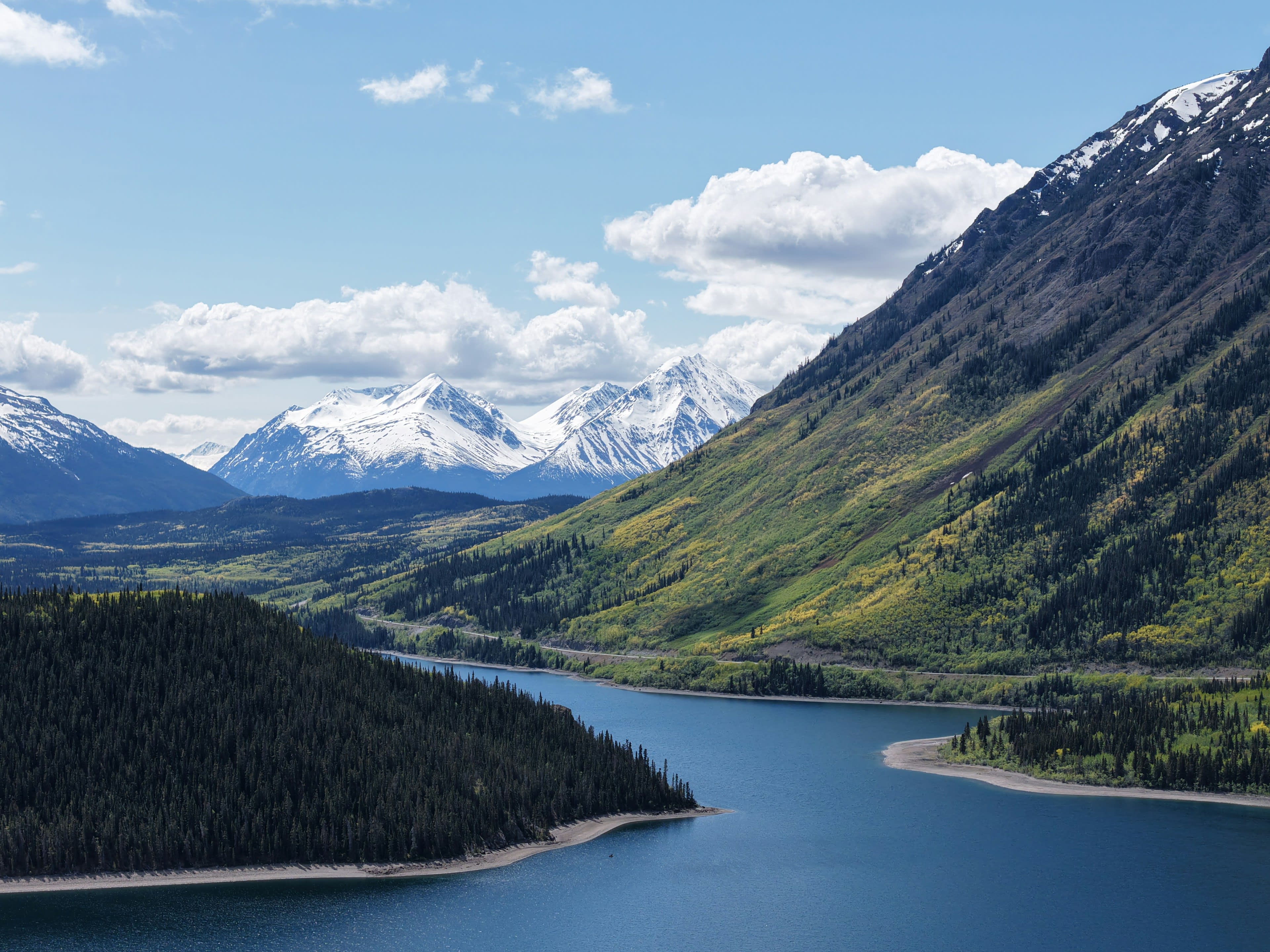Still lake water below scree mountains and soft evening cloud in Kluane