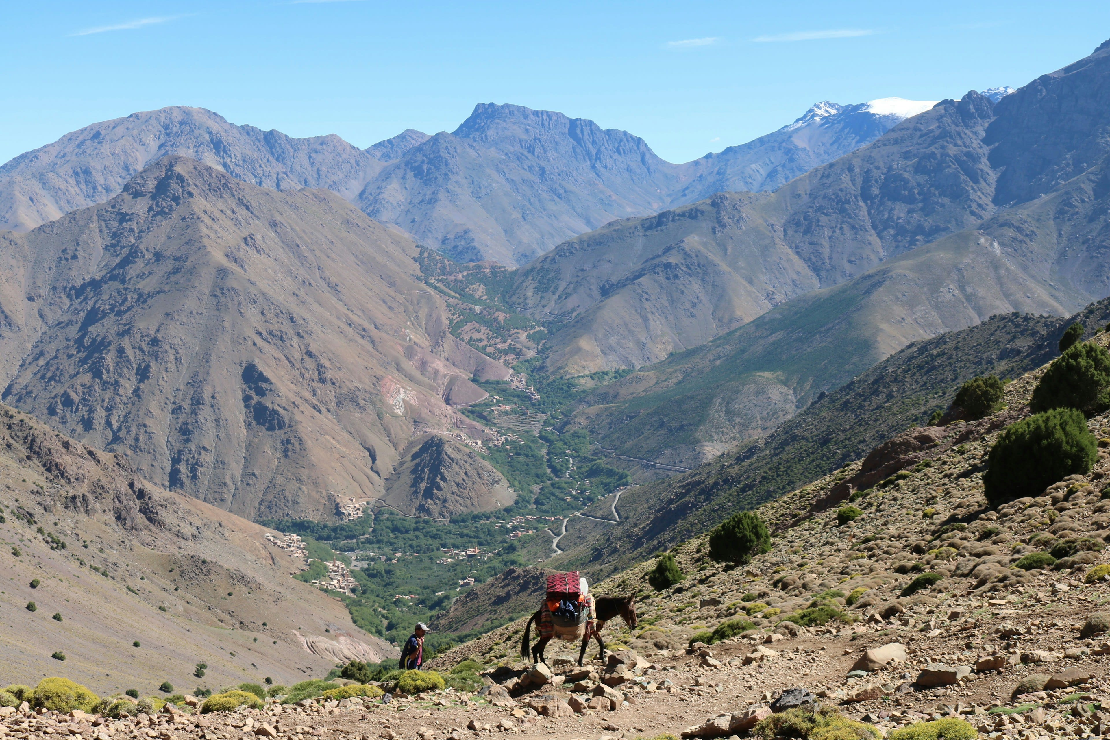 A green mountain valley with terraced fields below a high rocky range
