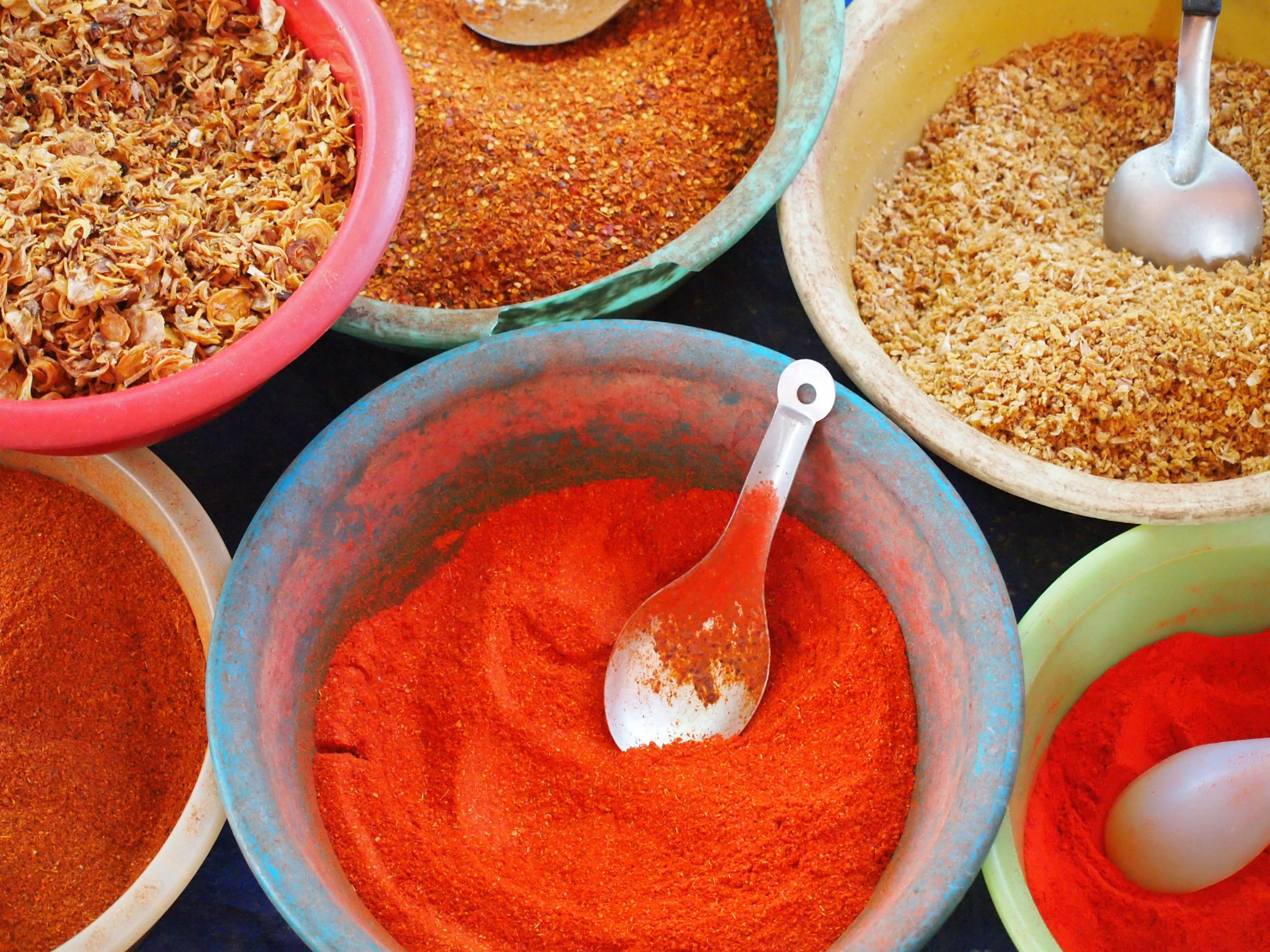 Enamel bowls of red chilli pastes and spices laid out on a market table