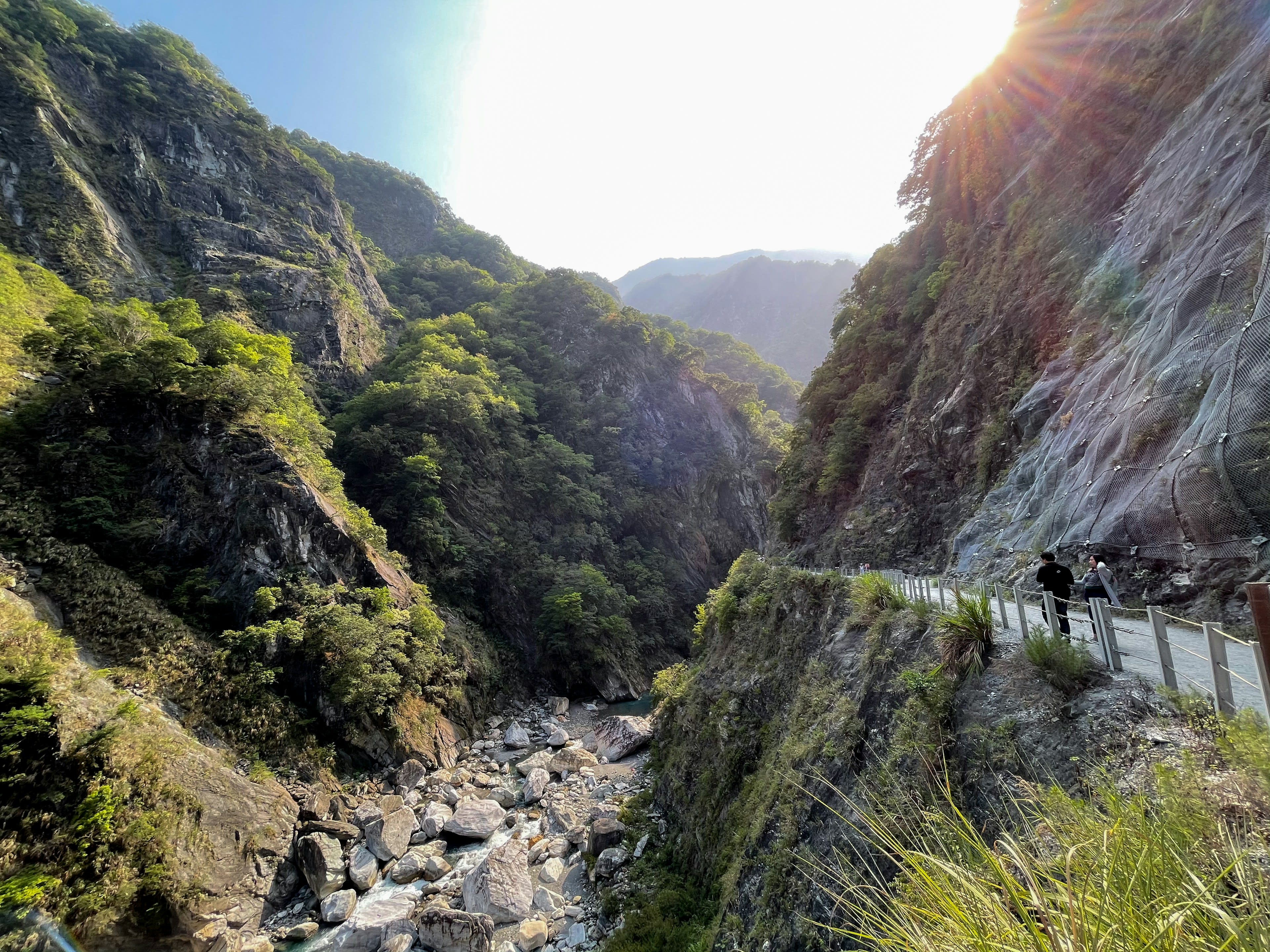 A road cut into the side of a deep marble gorge with sunlight coming down into it
