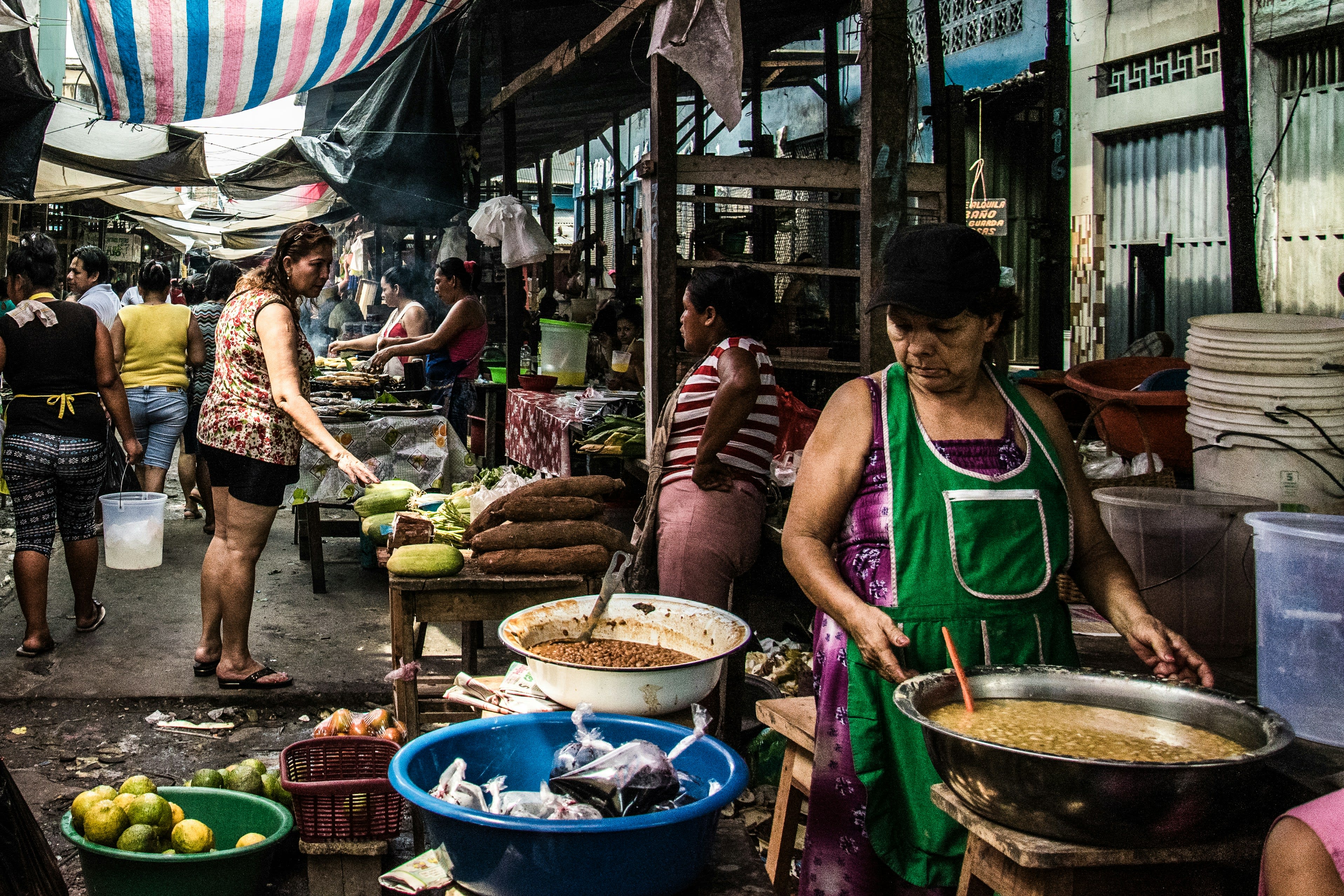 A woman serving food from big pots at a busy outdoor market