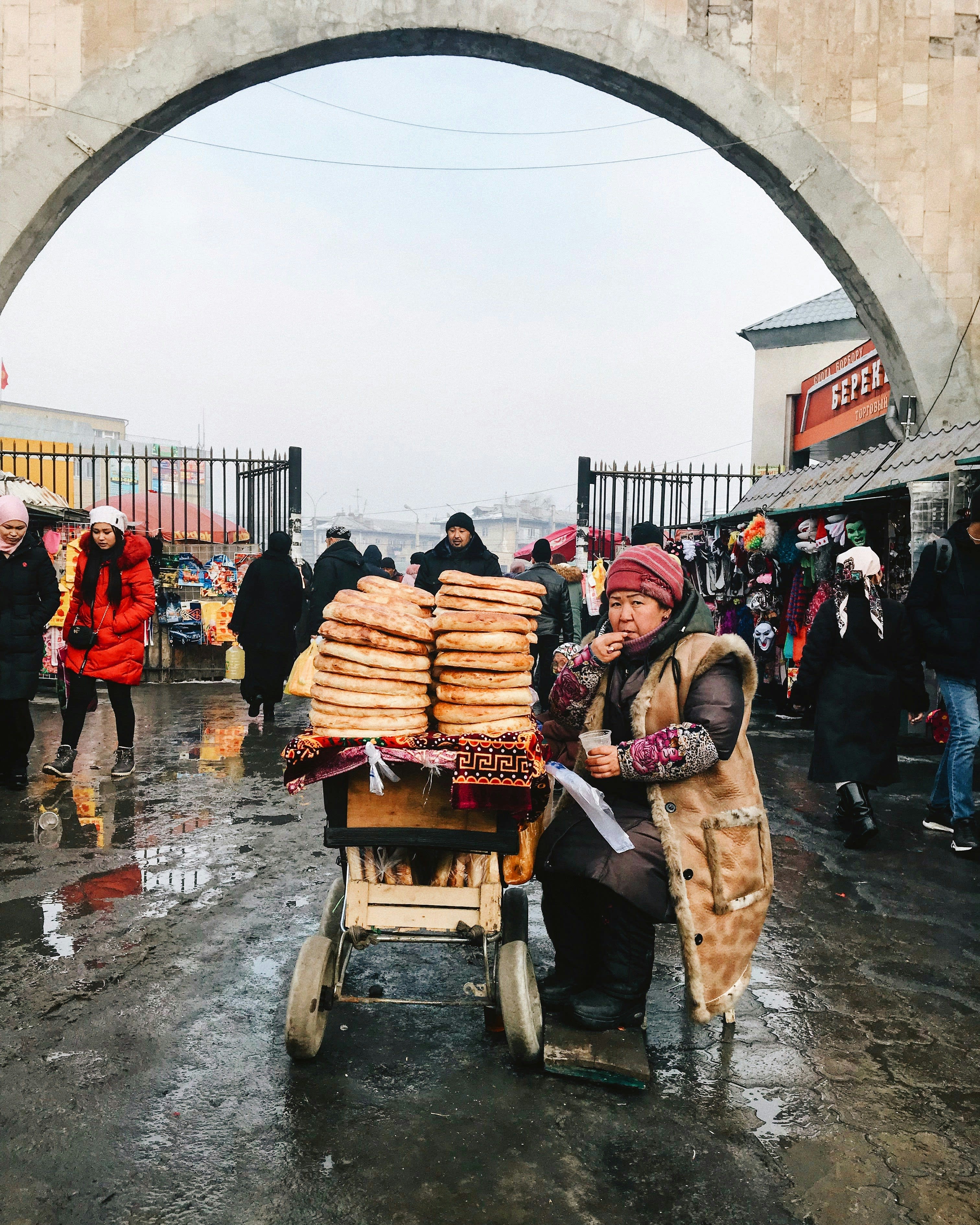 People pushing a cart stacked with flatbreads through a market gateway