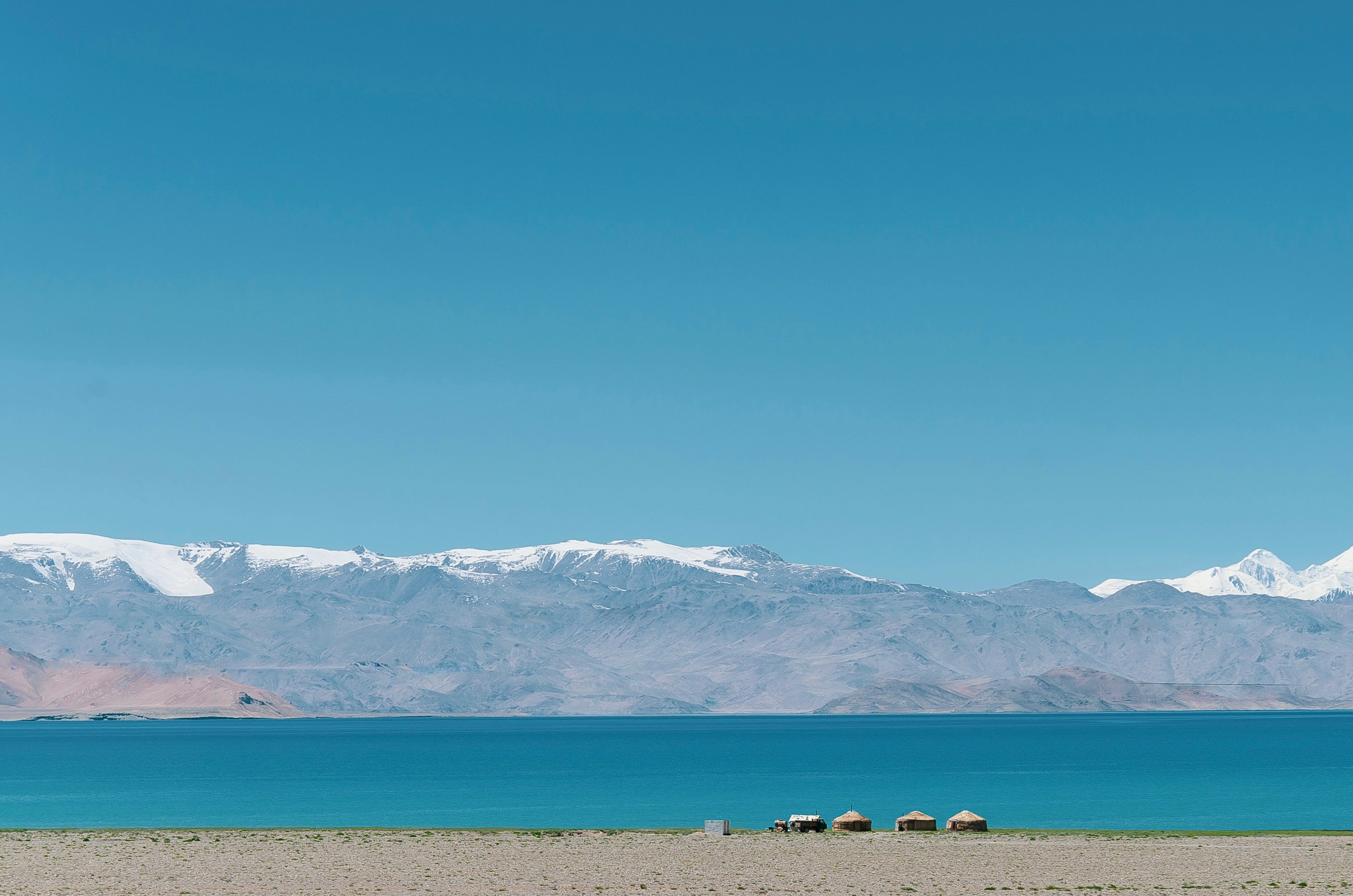 A deep blue high-altitude lake below a wall of snow-capped mountains