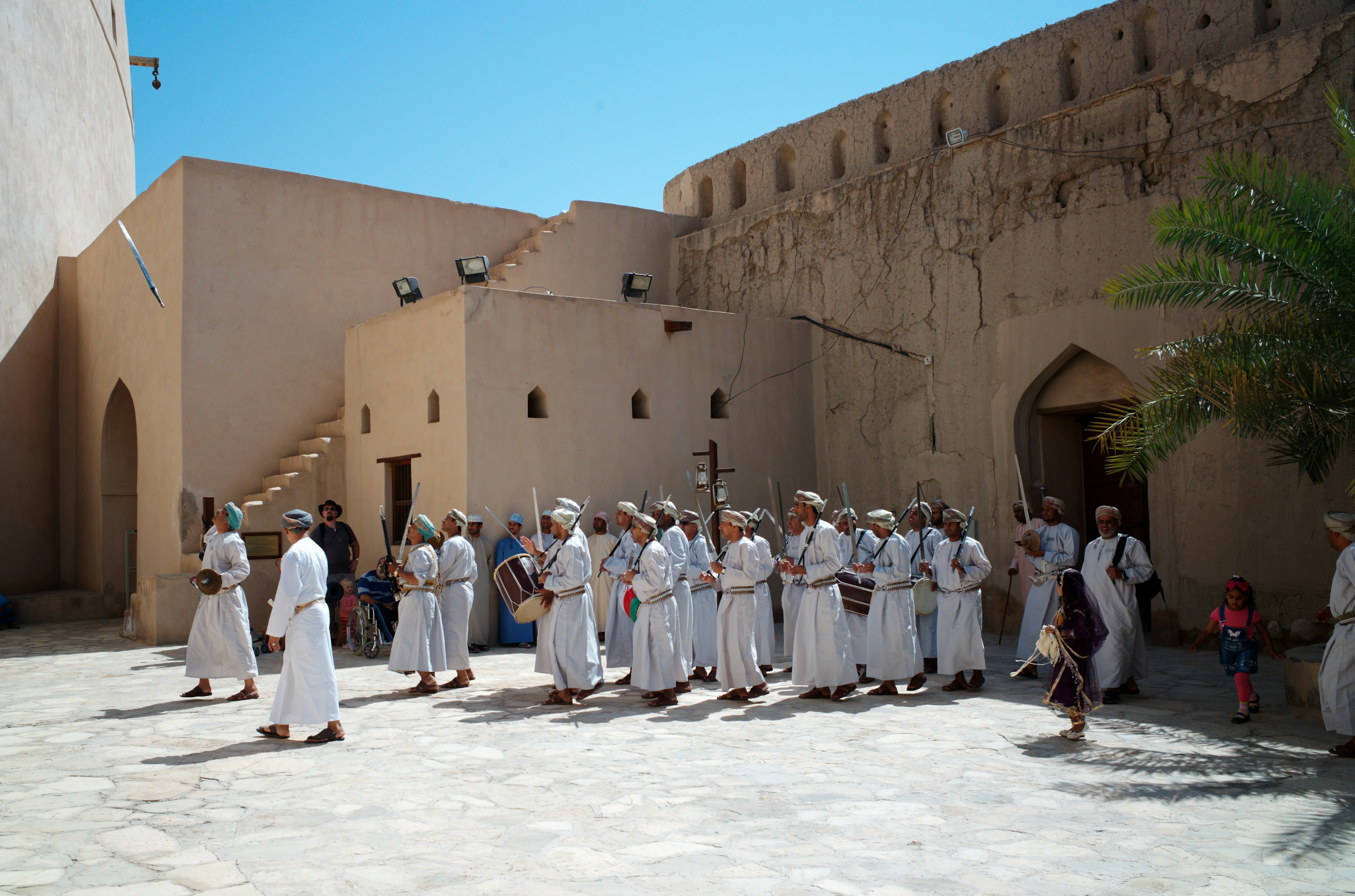 A group in white robes walking through a fort courtyard