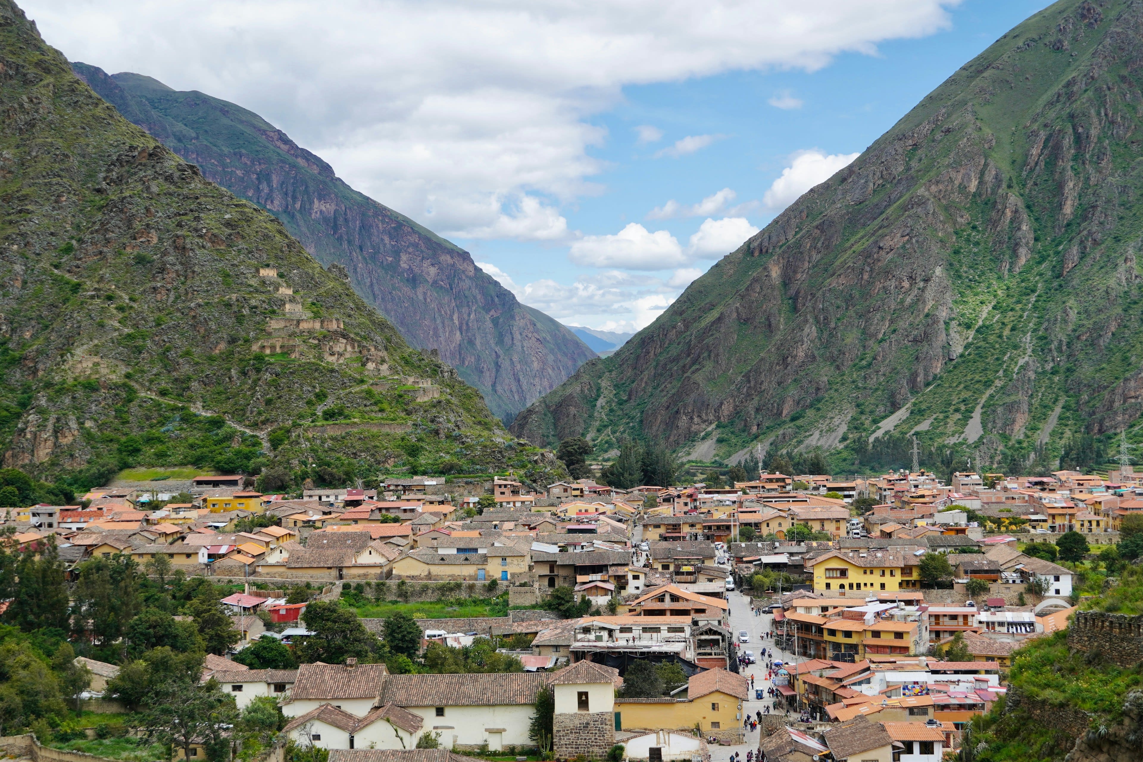 A stone village in a valley beneath steep mountains under heavy sky