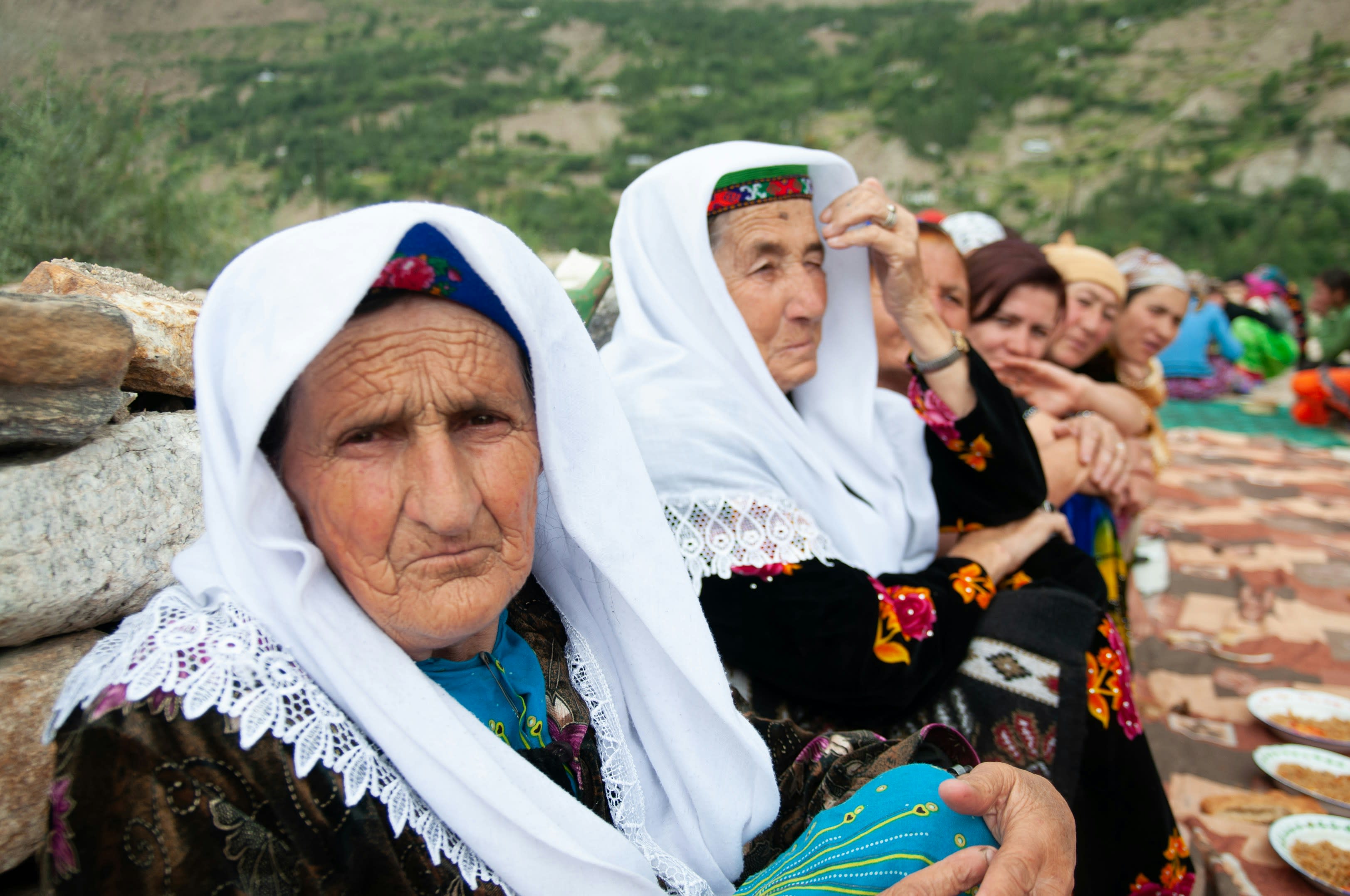 Wakhi women in white headscarves sitting together outdoors
