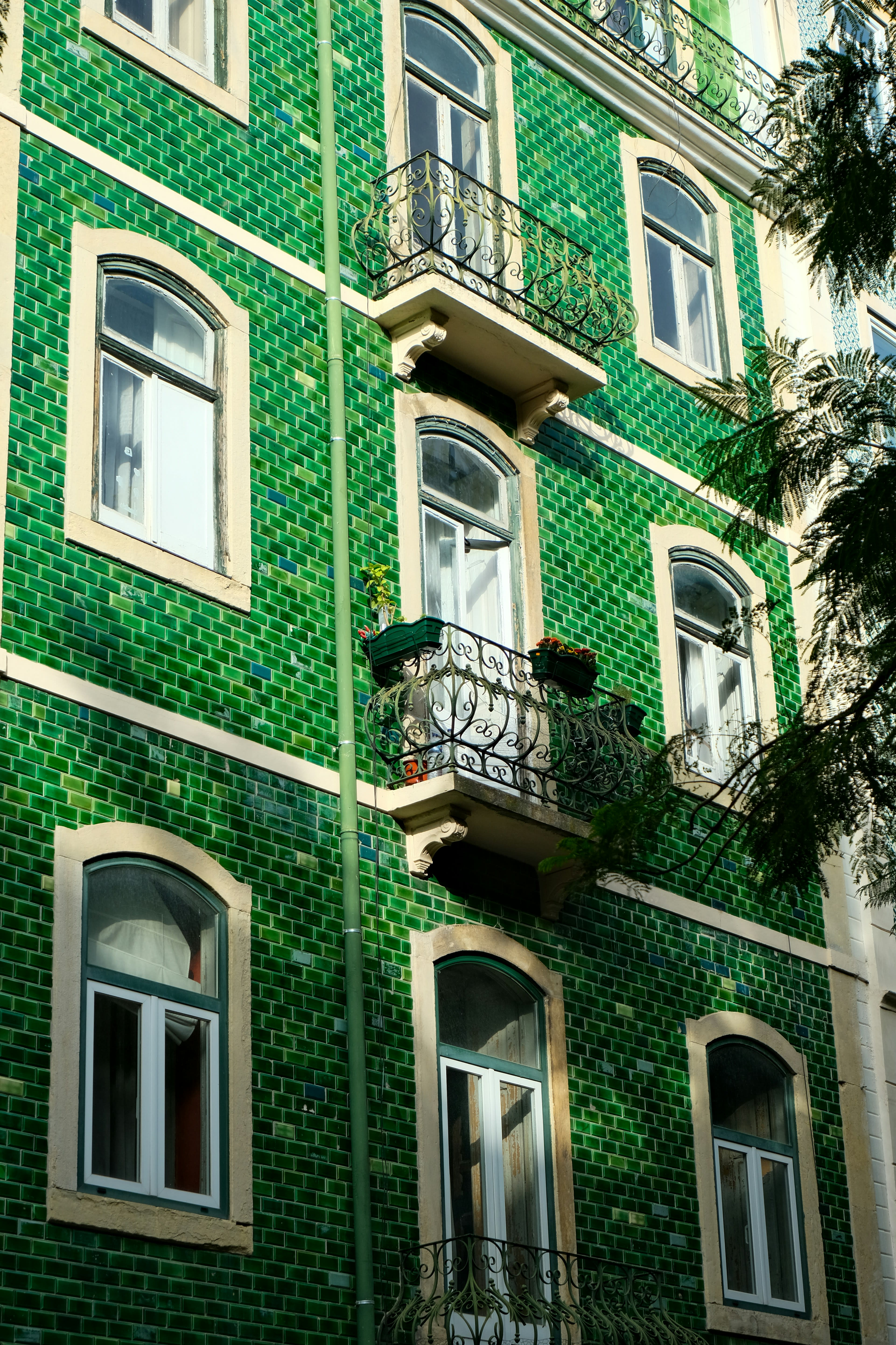 A building faced in deep green glazed tiles with white window frames