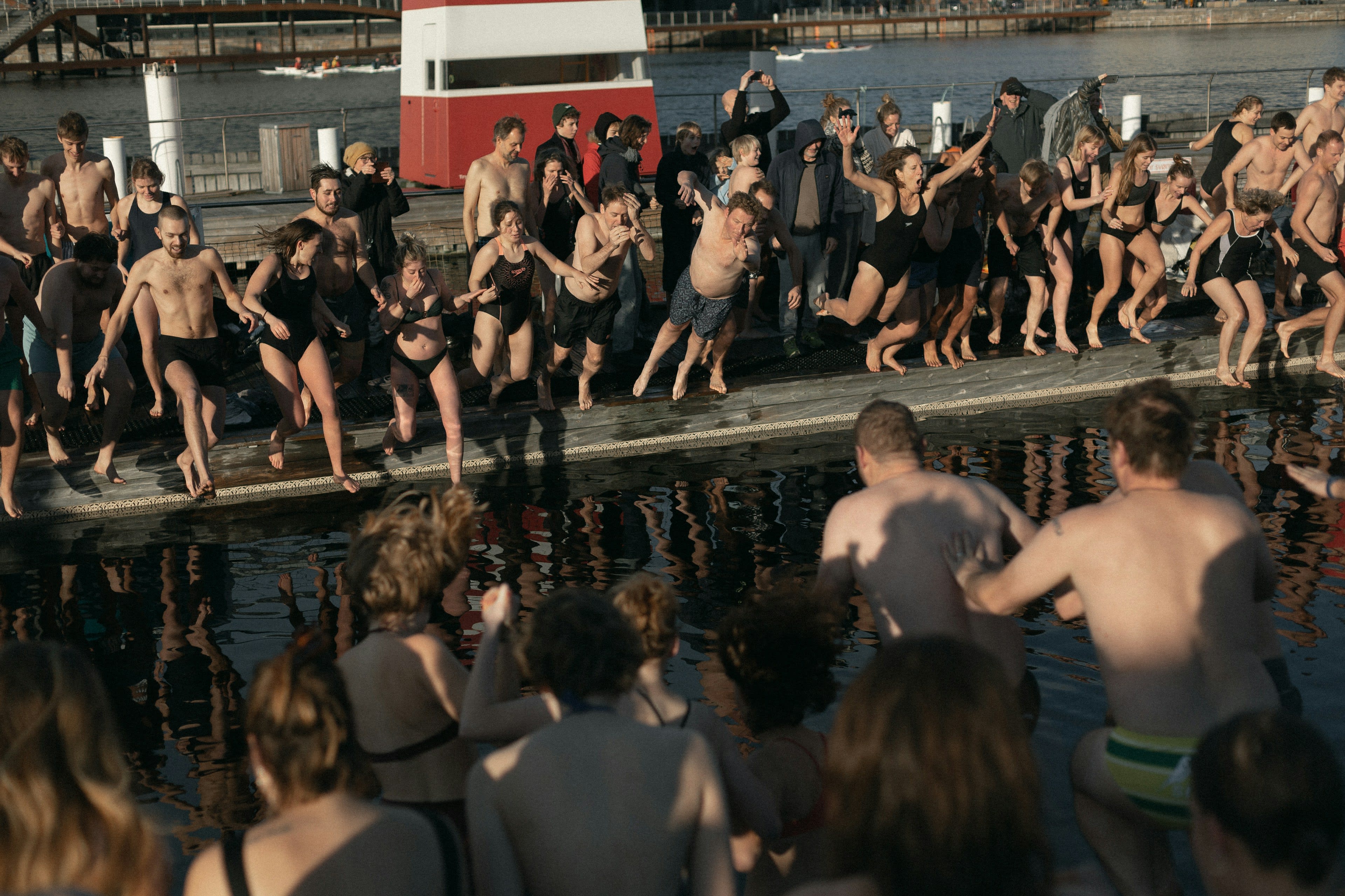 Swimmers gathered at the edge of a harbour bath about to jump in