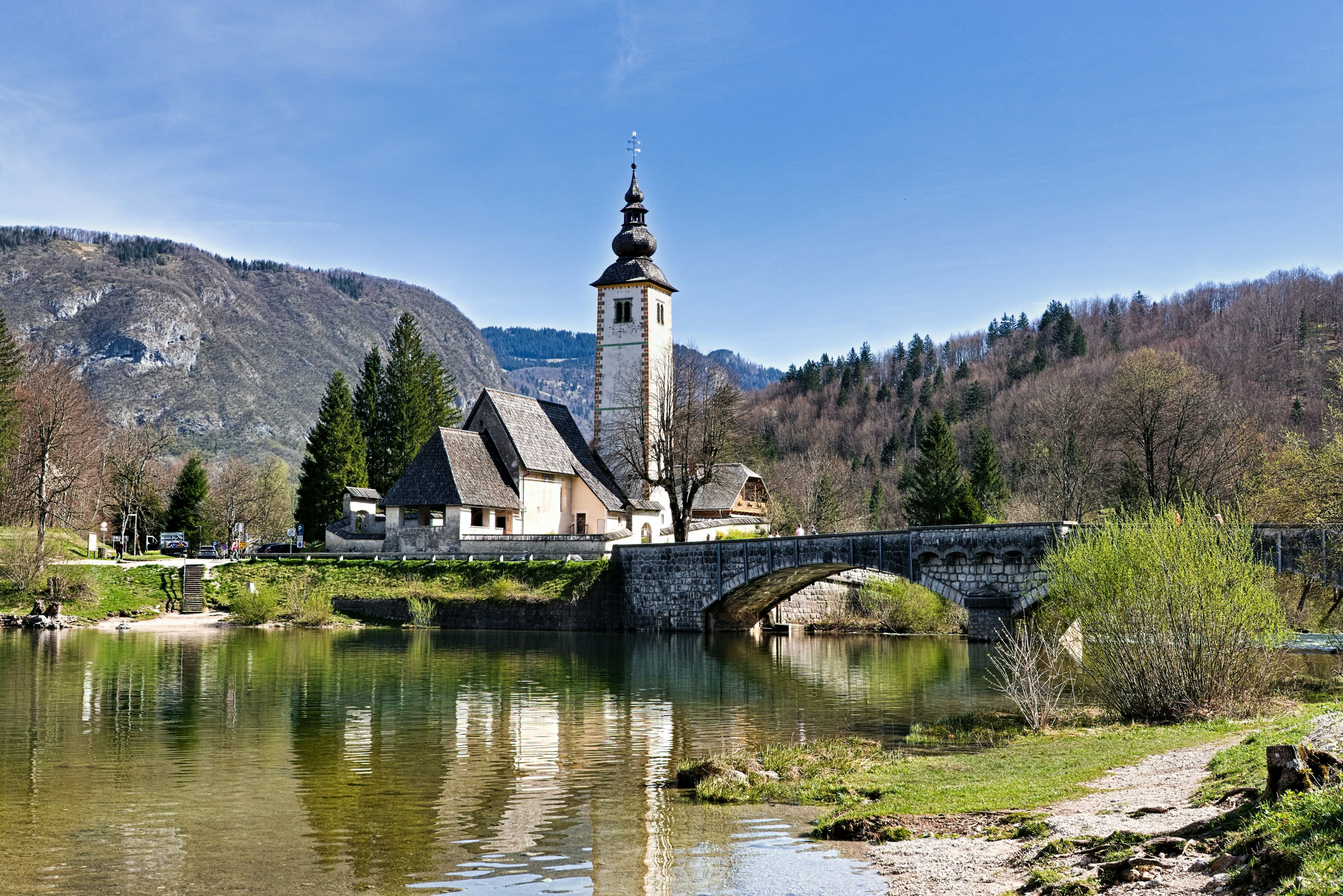 A small stone church and bridge at the head of an alpine lake