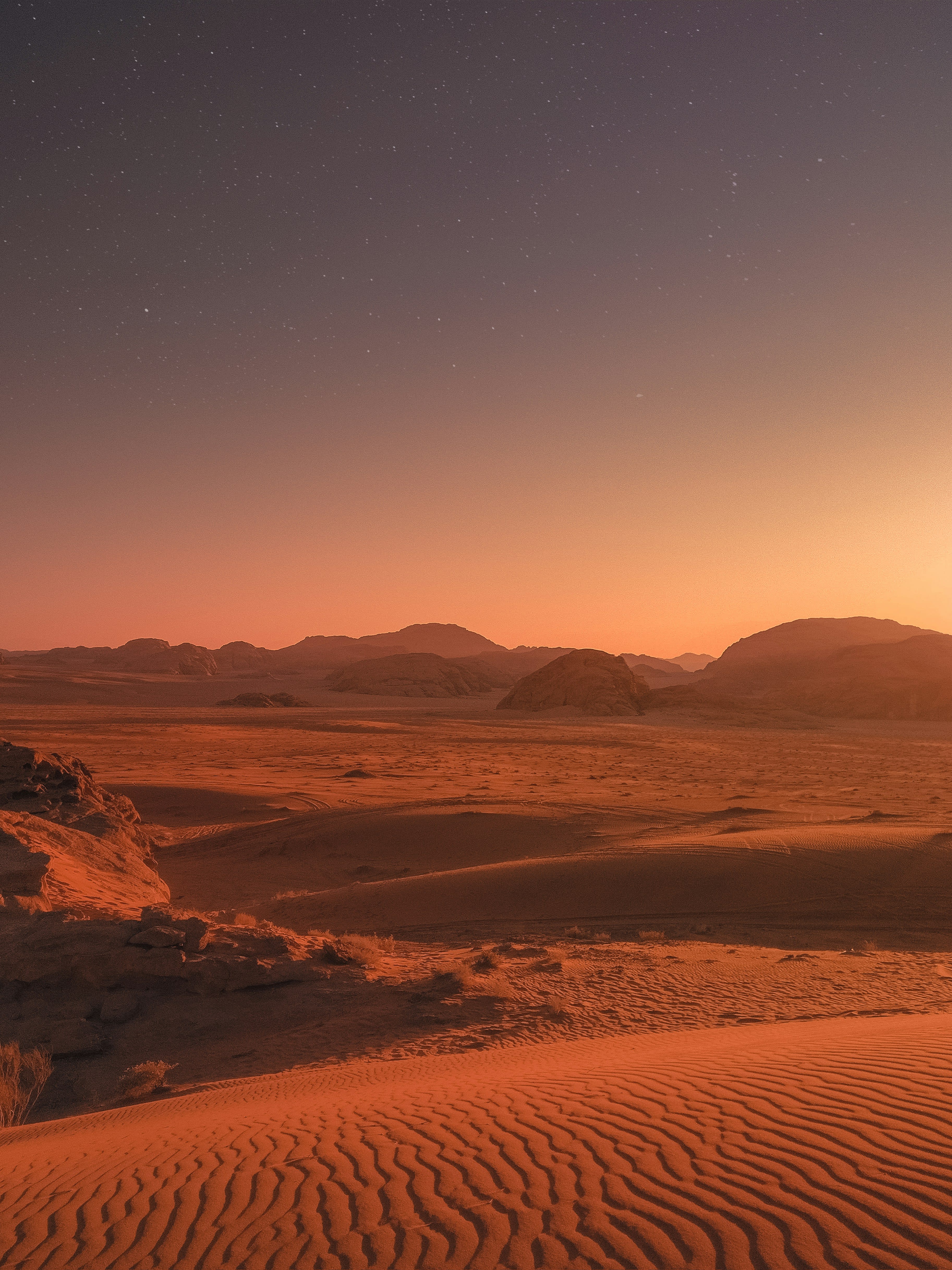 A steep red sand dune ridge against a dusk sky