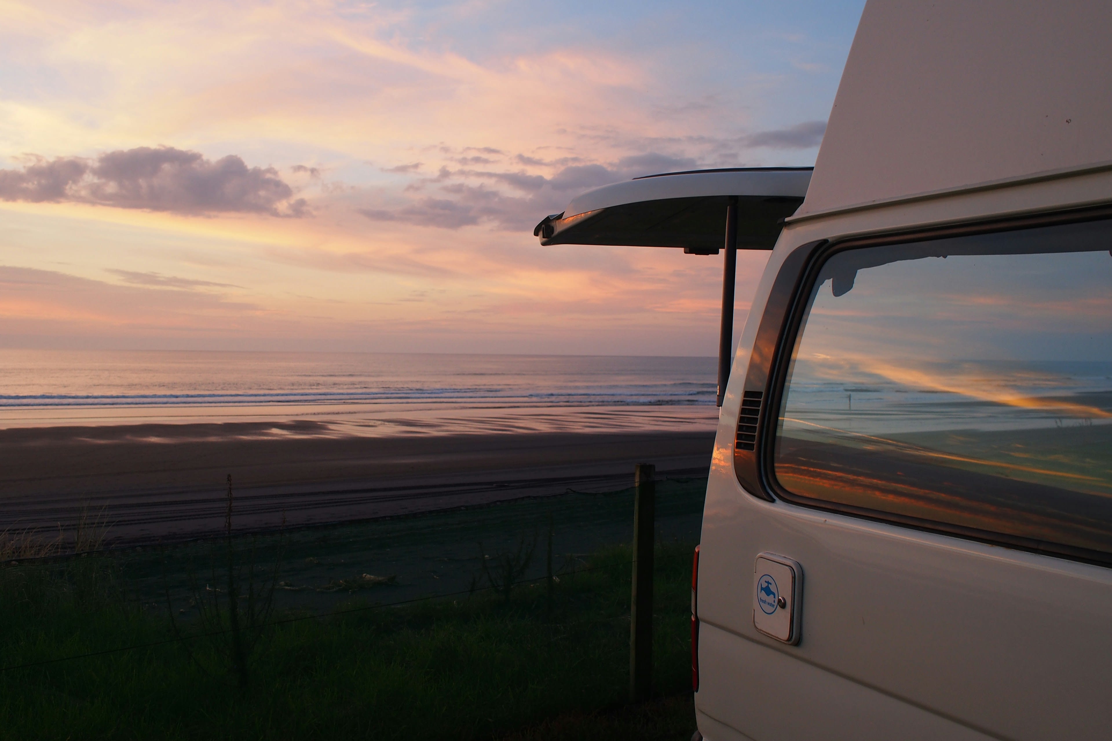 The open sliding door of a campervan facing a soft sunrise