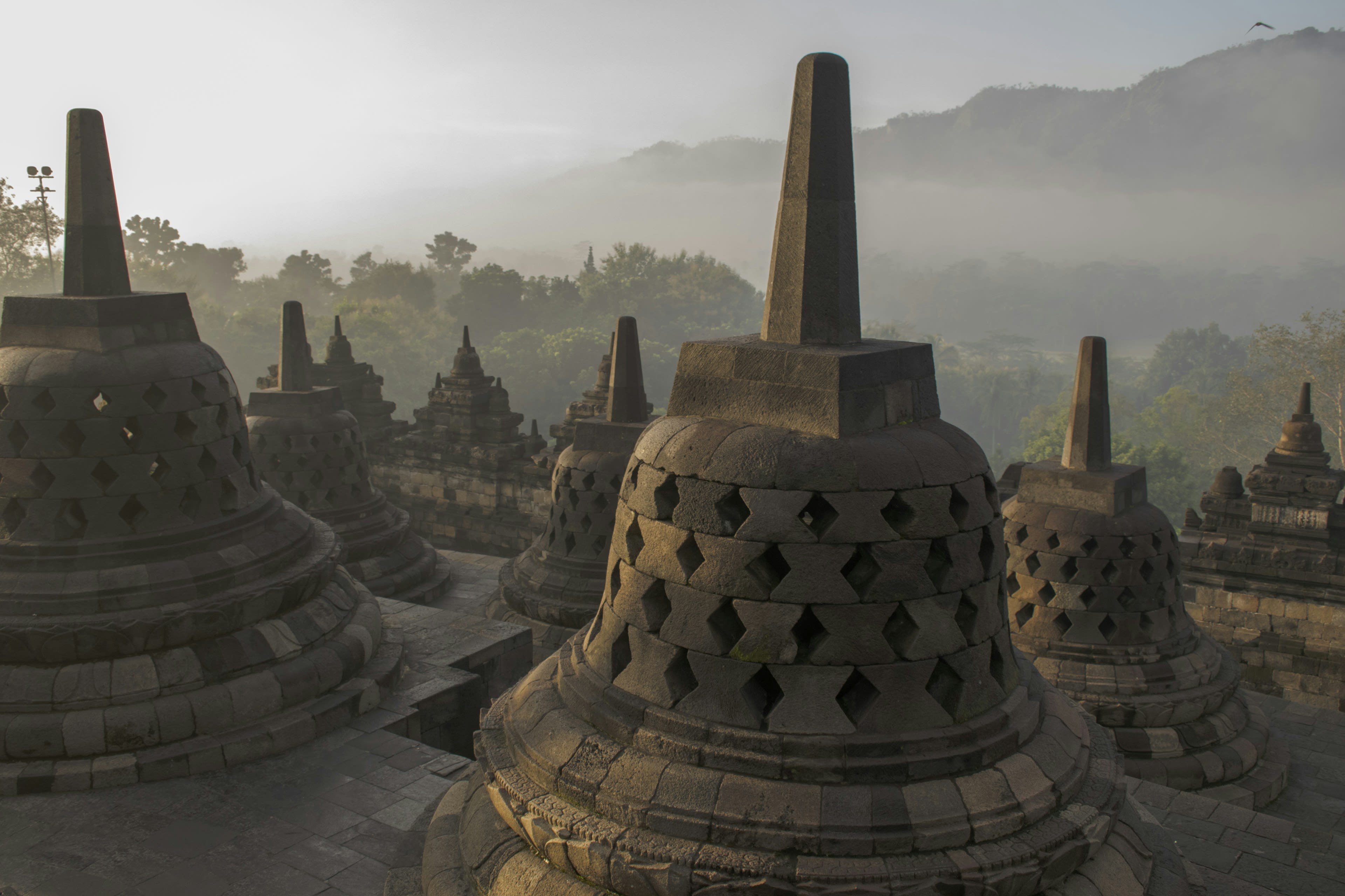 Stone bell stupas of Borobudur with hazy hills beyond