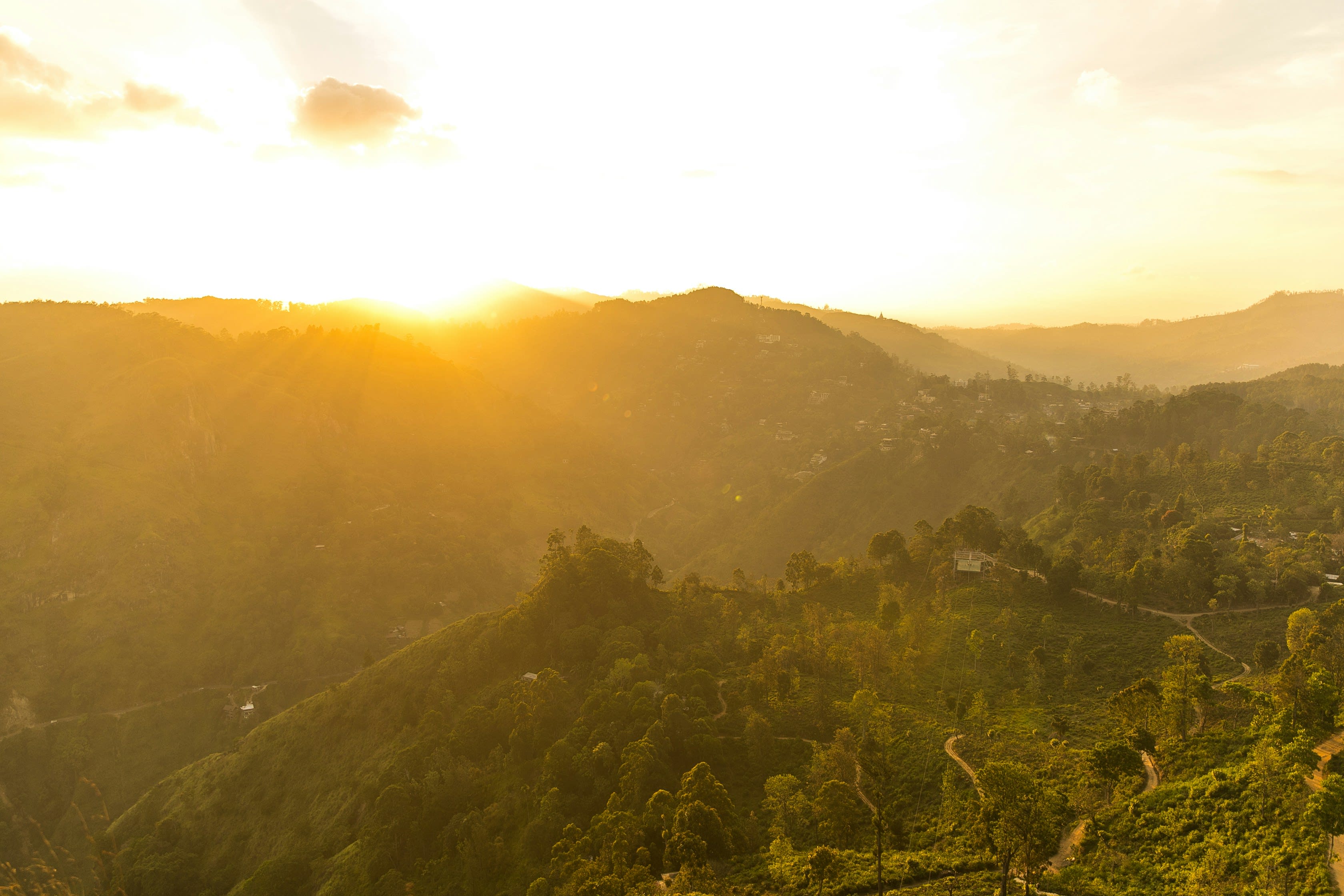 Sunset light over layered green hills seen through a mountain gap