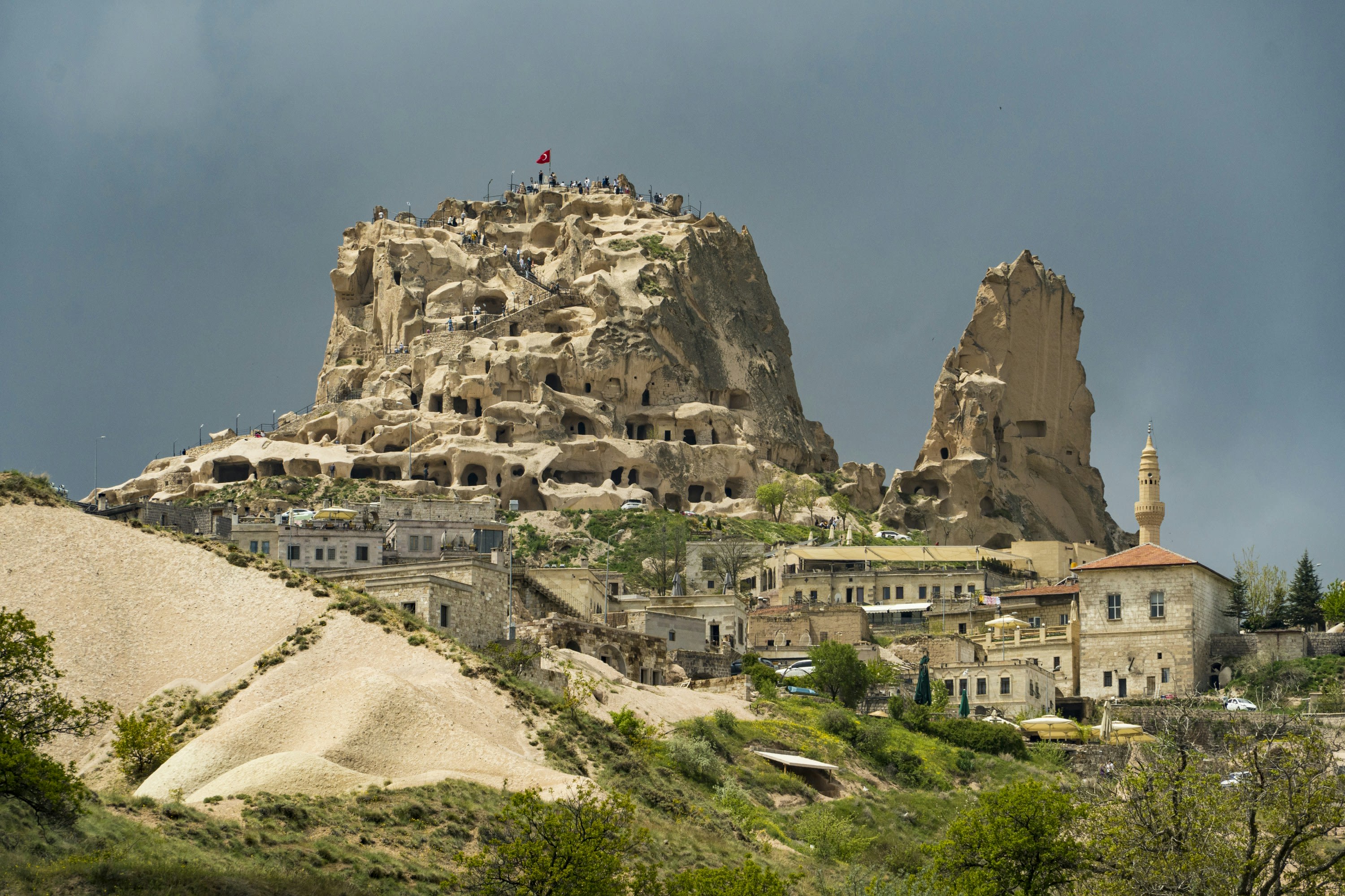 A huge rock outcrop riddled with carved windows rising over a town