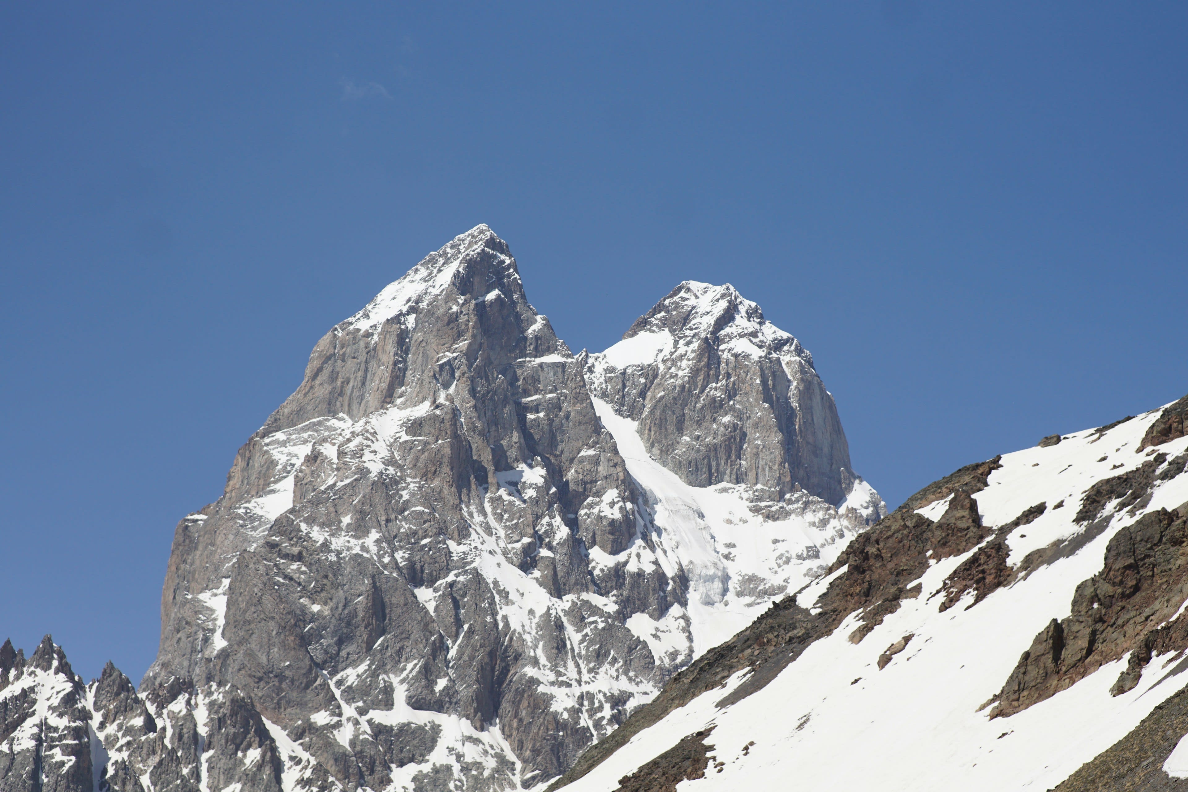 Twin snow-covered rock peaks against a clear blue sky